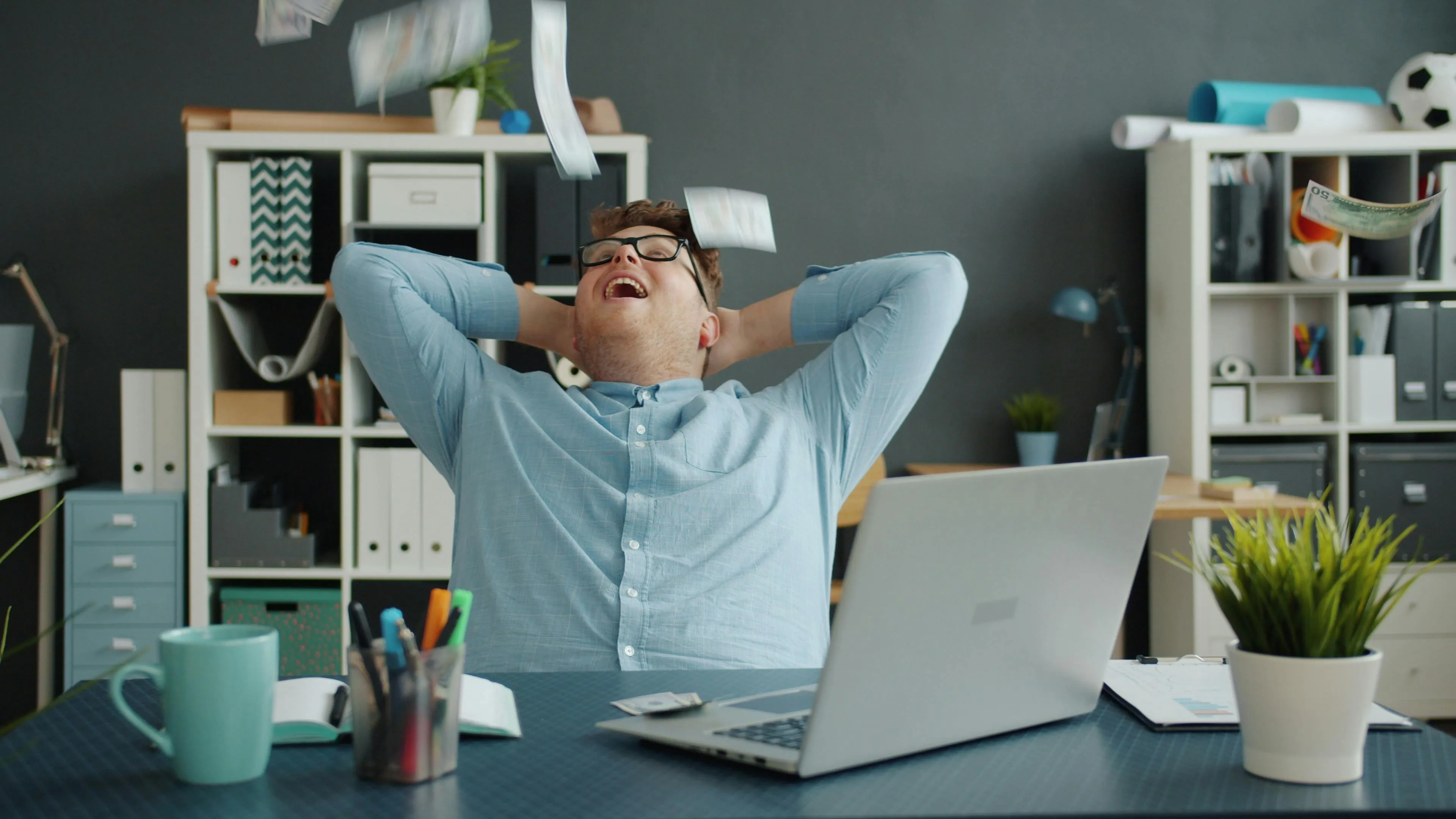 Man in casual office setting throwing money, feeling joyful about what job matches your soul and dream work perks.