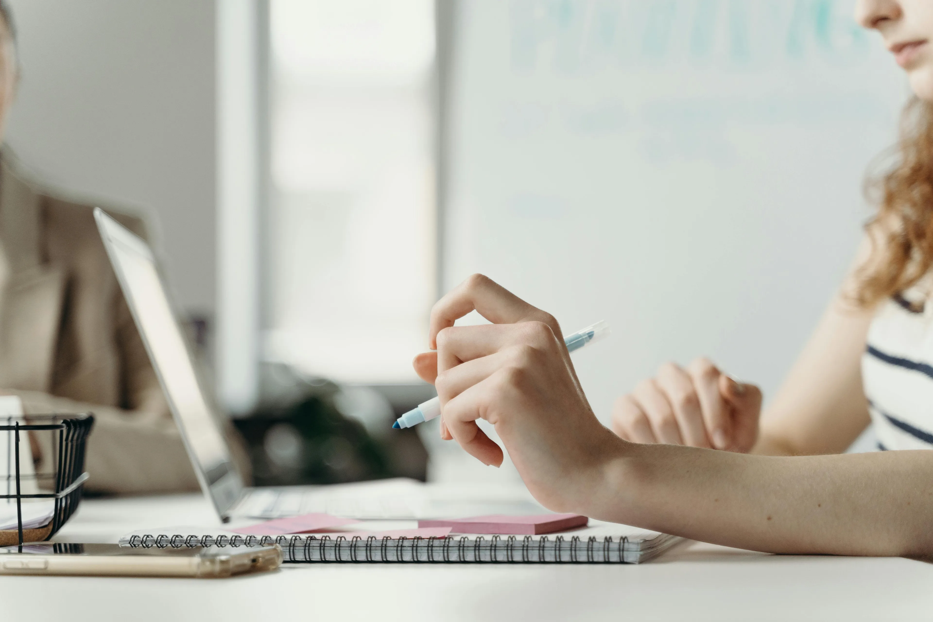Person holding a pen and working on a laptop with a notebook, exploring what job matches your soul concept.