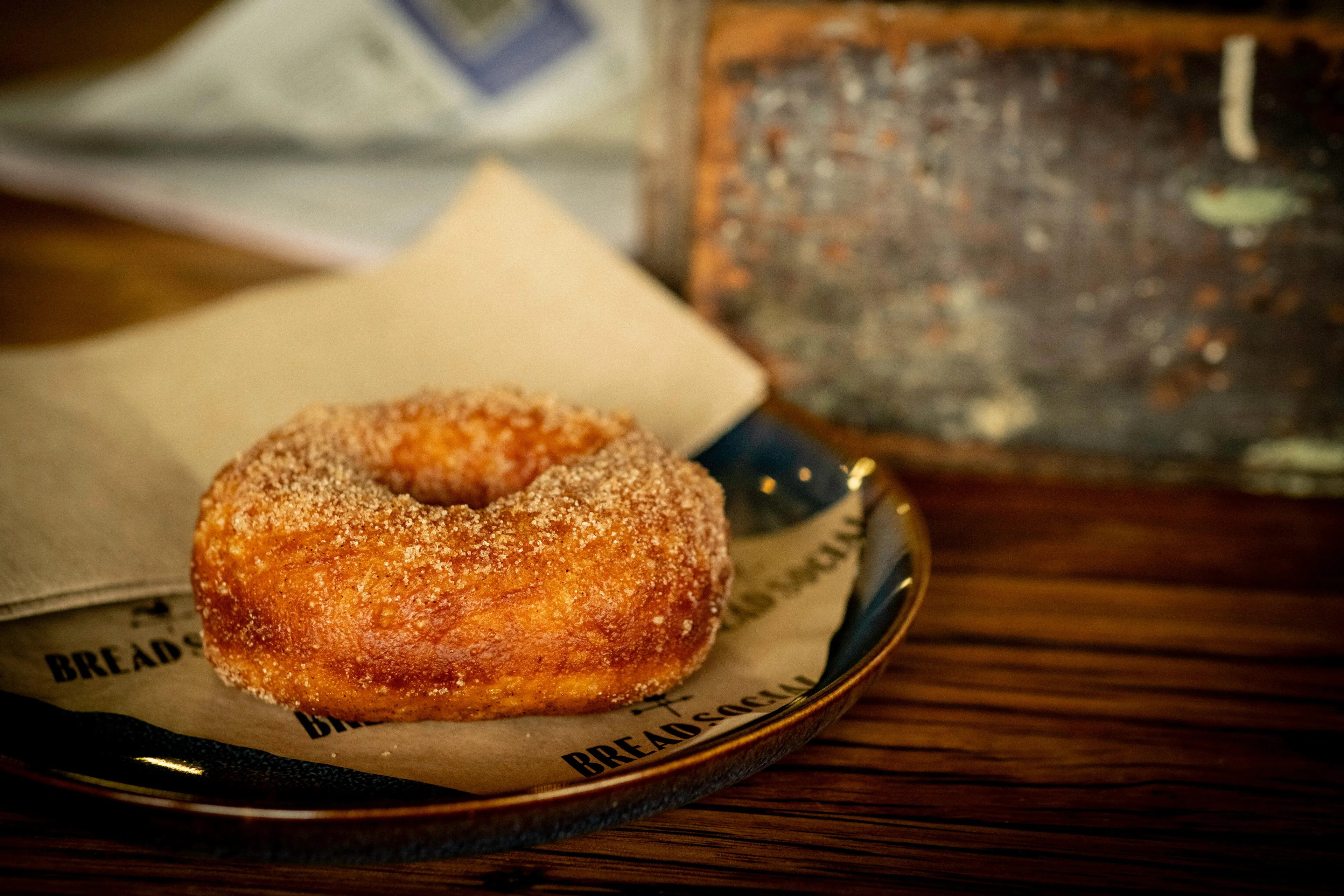 Homemade cinnamon donut on a plate with a rustic wooden background, showcasing a warm dessert option.