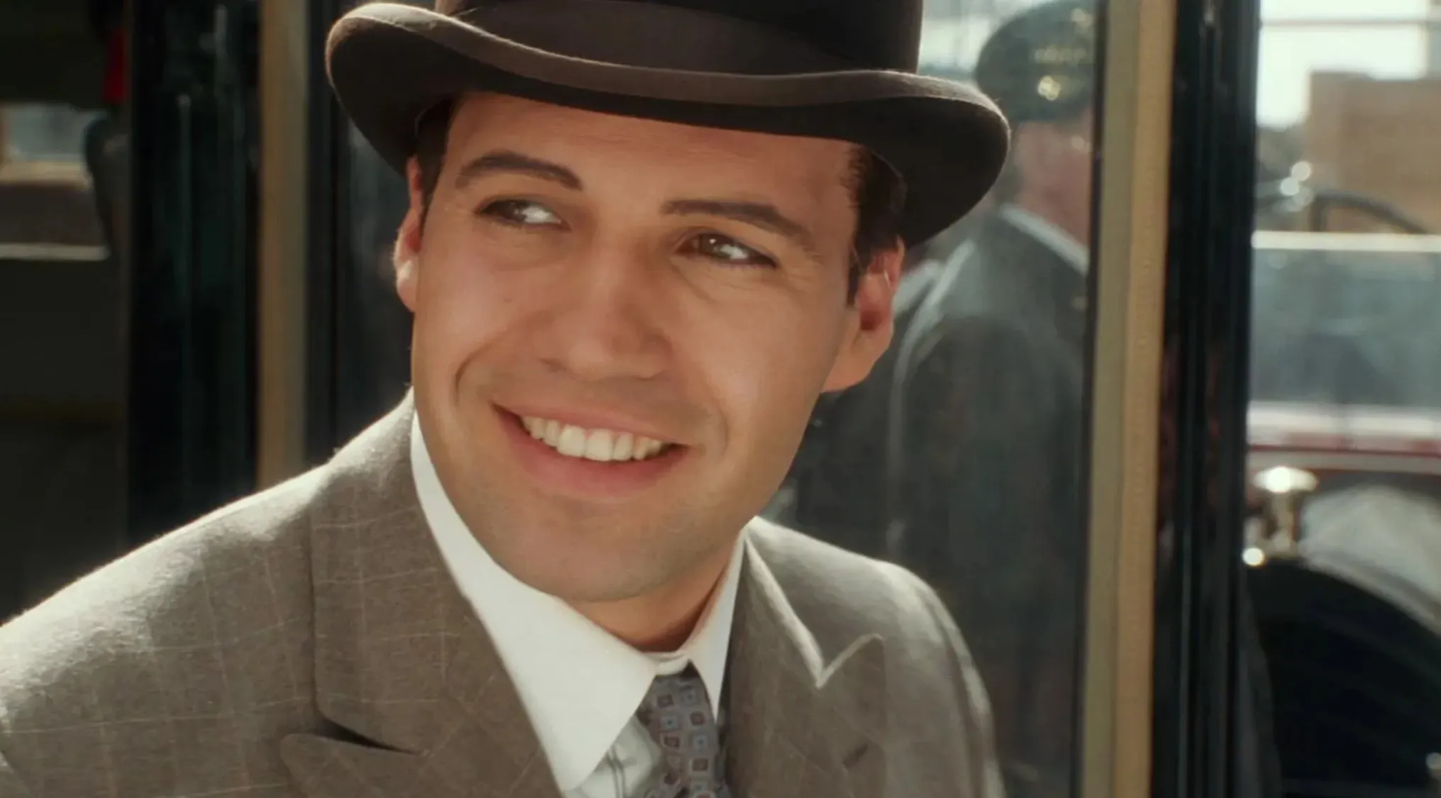 A wealthy, arrogant 80s and 90s villains style fiancé wearing a suit and hat, smiling inside a vintage car.