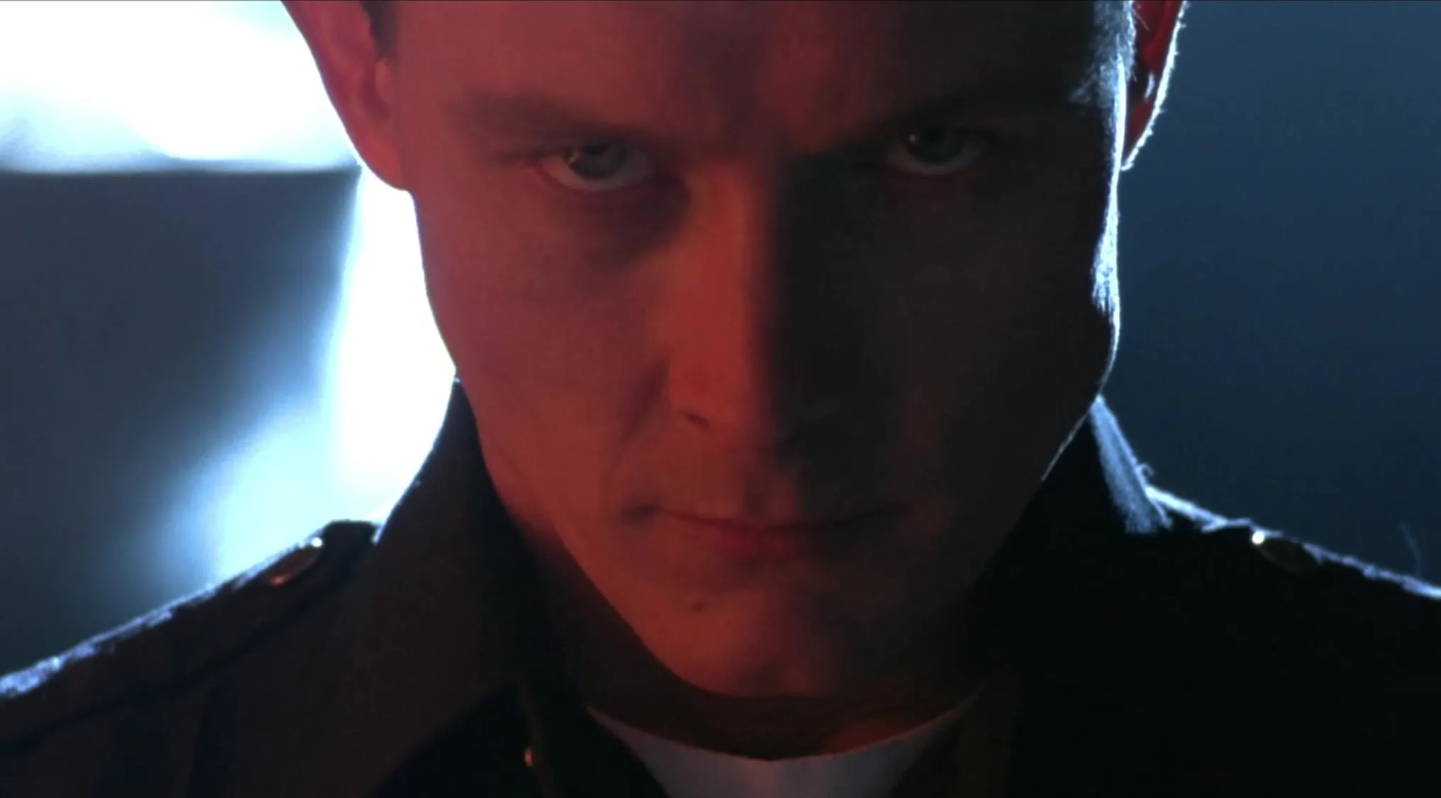 Close-up of a cold, emotionless 80s and 90s villain with intense eyes, known as a nearly indestructible hunter.