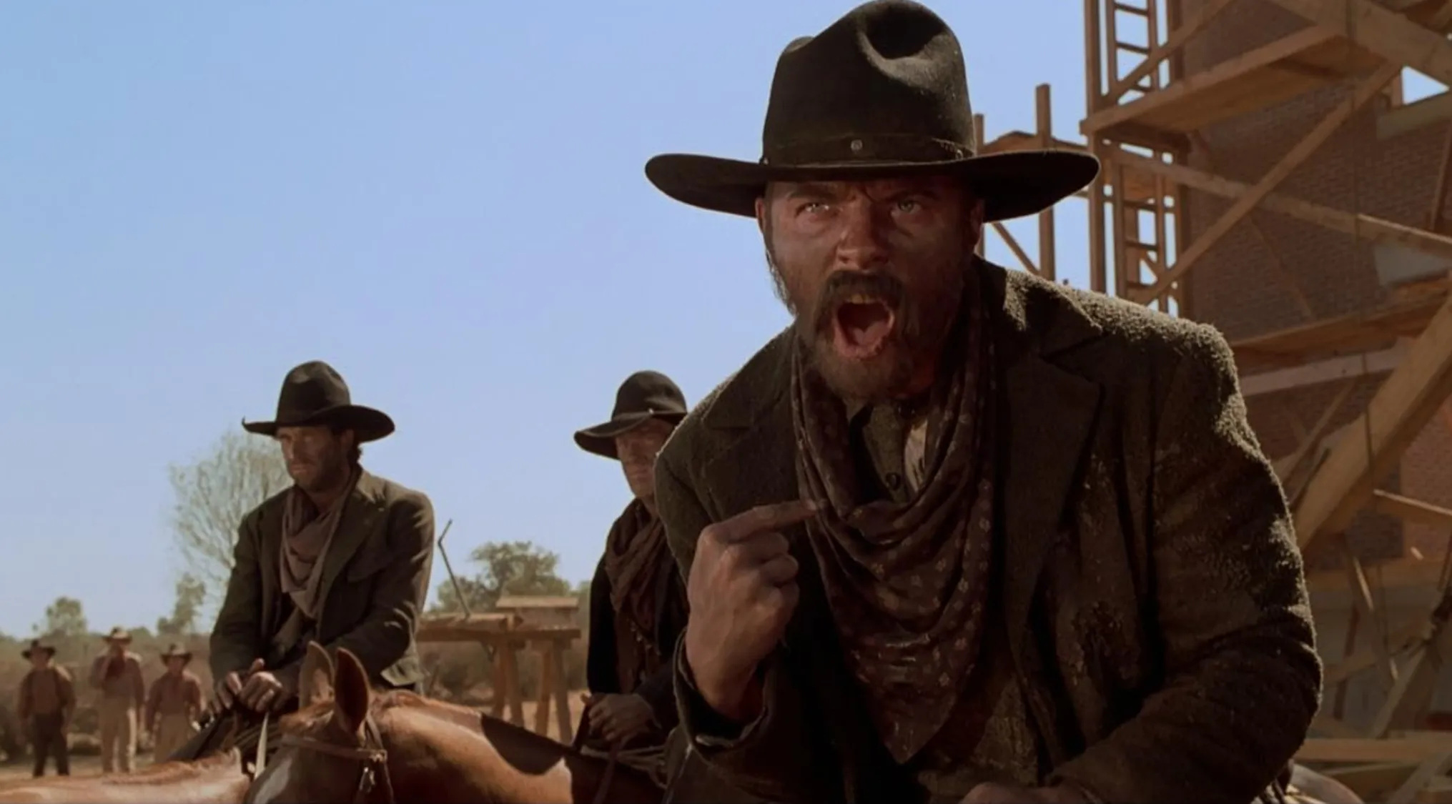Wild west outlaw with a dangerous temper and arrogance, shouting aggressively in a dusty western town setting.