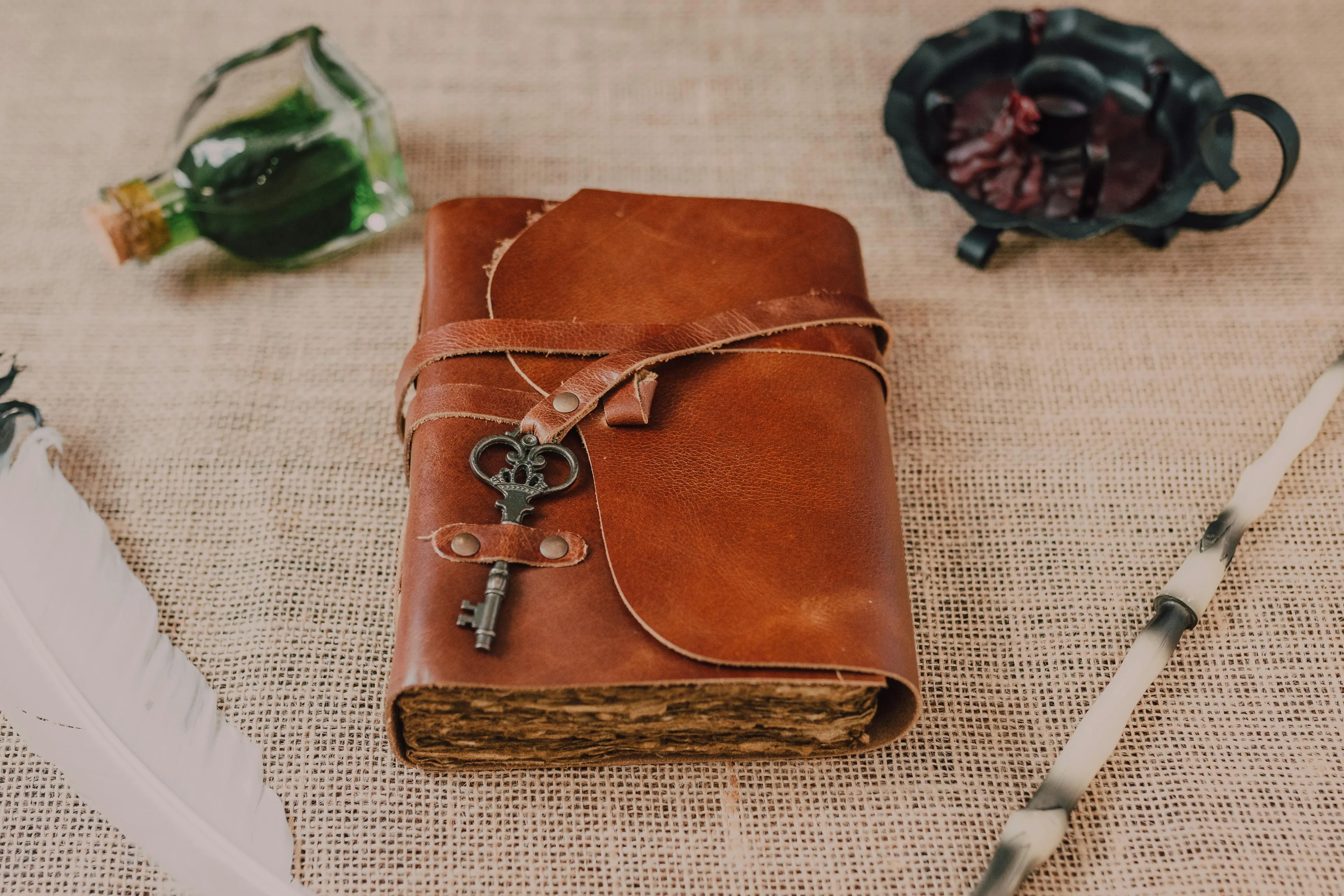 Old leather travel journal with vintage key and rustic items on a textured cloth surface for restoration project.