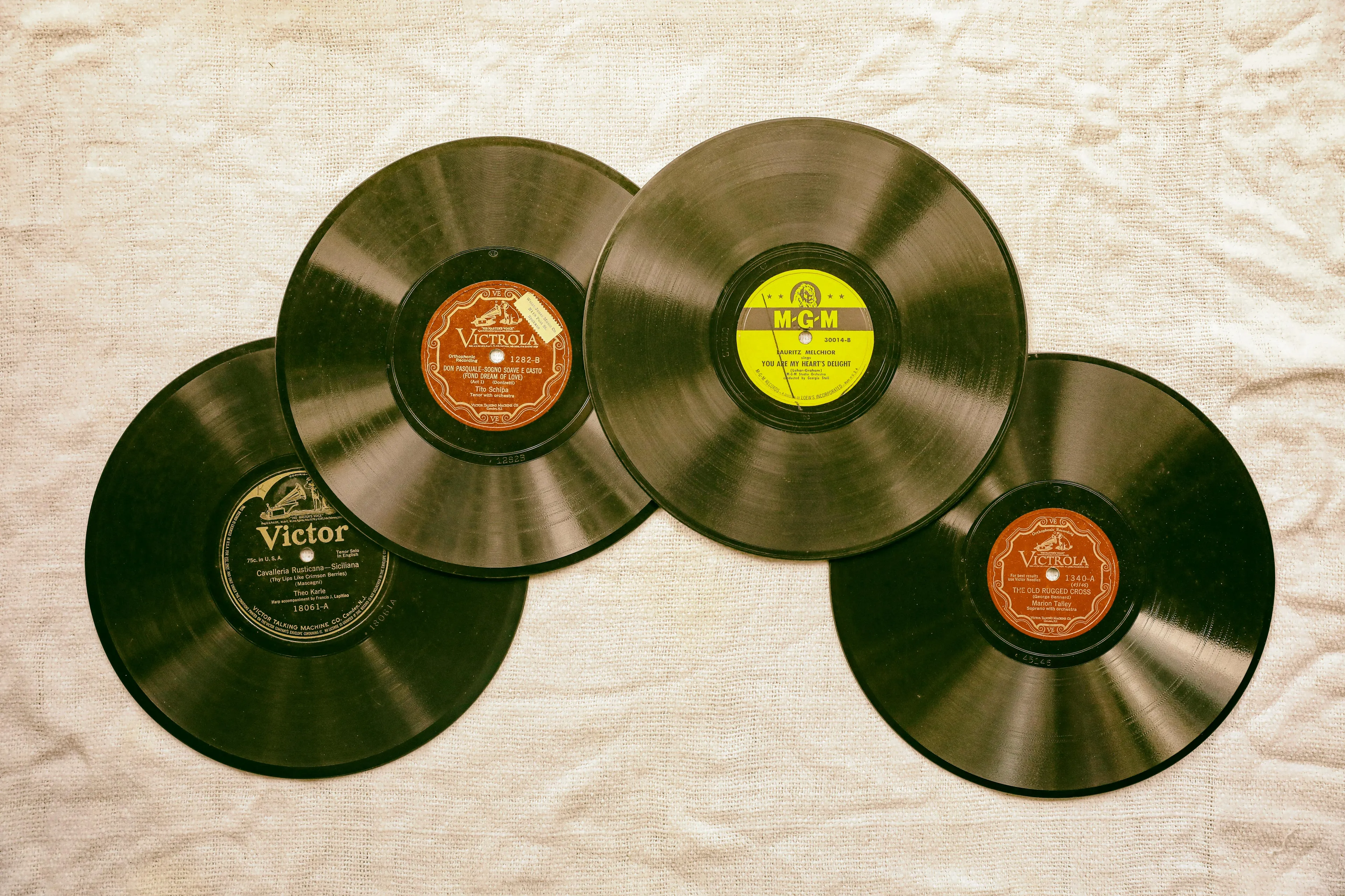 A collection of vintage vinyl records laid out on a textured surface, ready for restoration and playback.