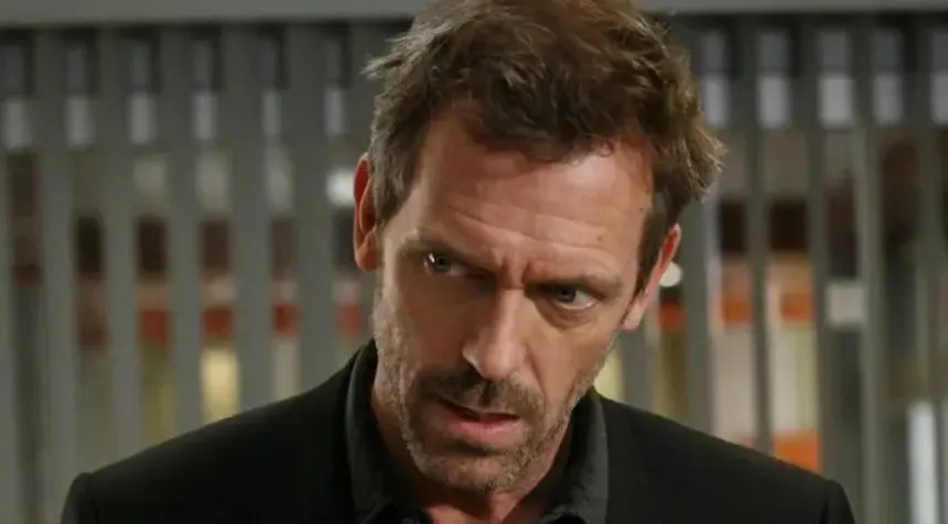 Dr. House with intense expression in office setting, portraying the fictional boss team members might want to work for.