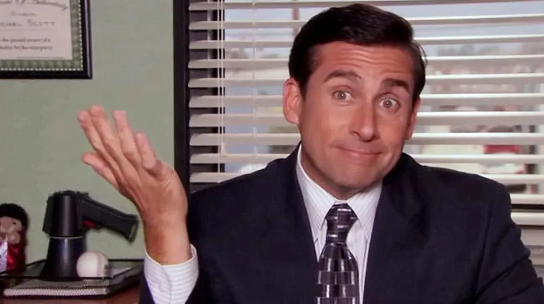 Michael Scott from The Office shrugging in an office setting, portraying a fictional boss you might want to work for.