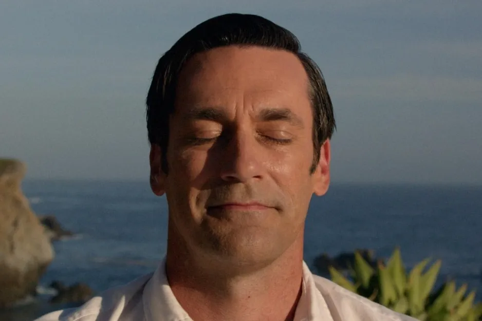 Man with closed eyes smiling gently near ocean, representing the tone of Mad Men TV show character.