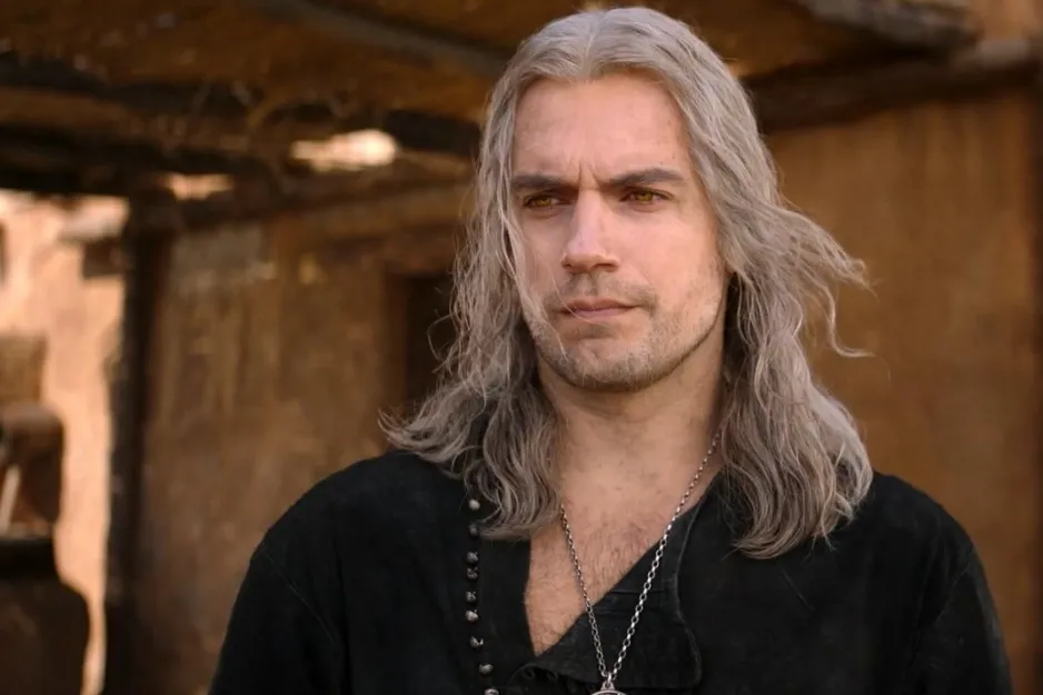 A character from The Witcher with long white hair and yellow eyes, dressed in medieval fantasy attire outdoors.
