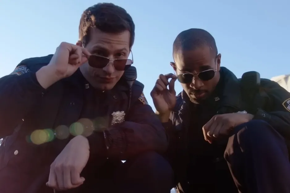 Two Brooklyn Nine-Nine characters in police uniforms adjusting sunglasses outdoors under clear sky.