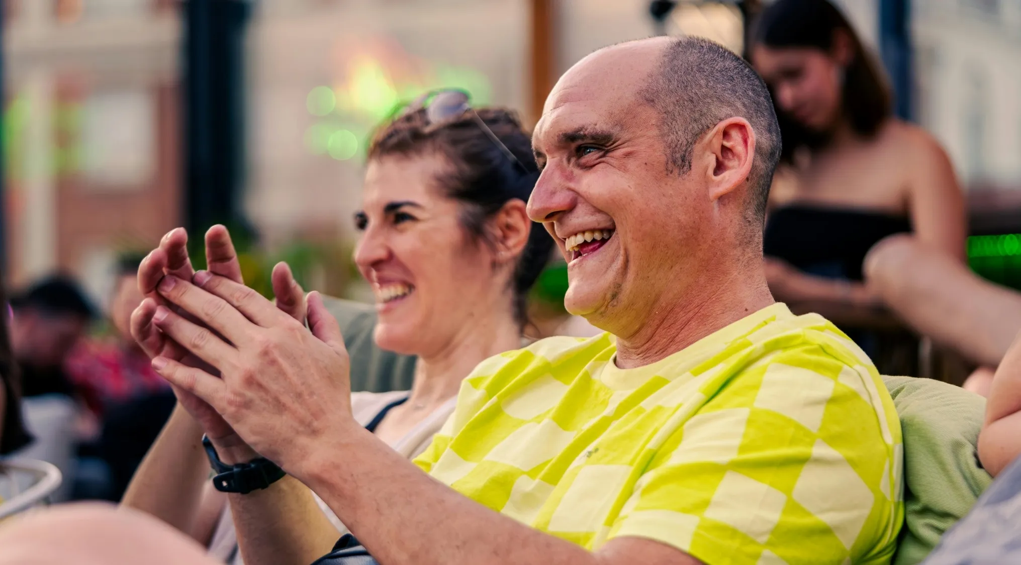 Two people laughing and clapping while enjoying comedies, highlighting TV shows composed entirely of comedies.