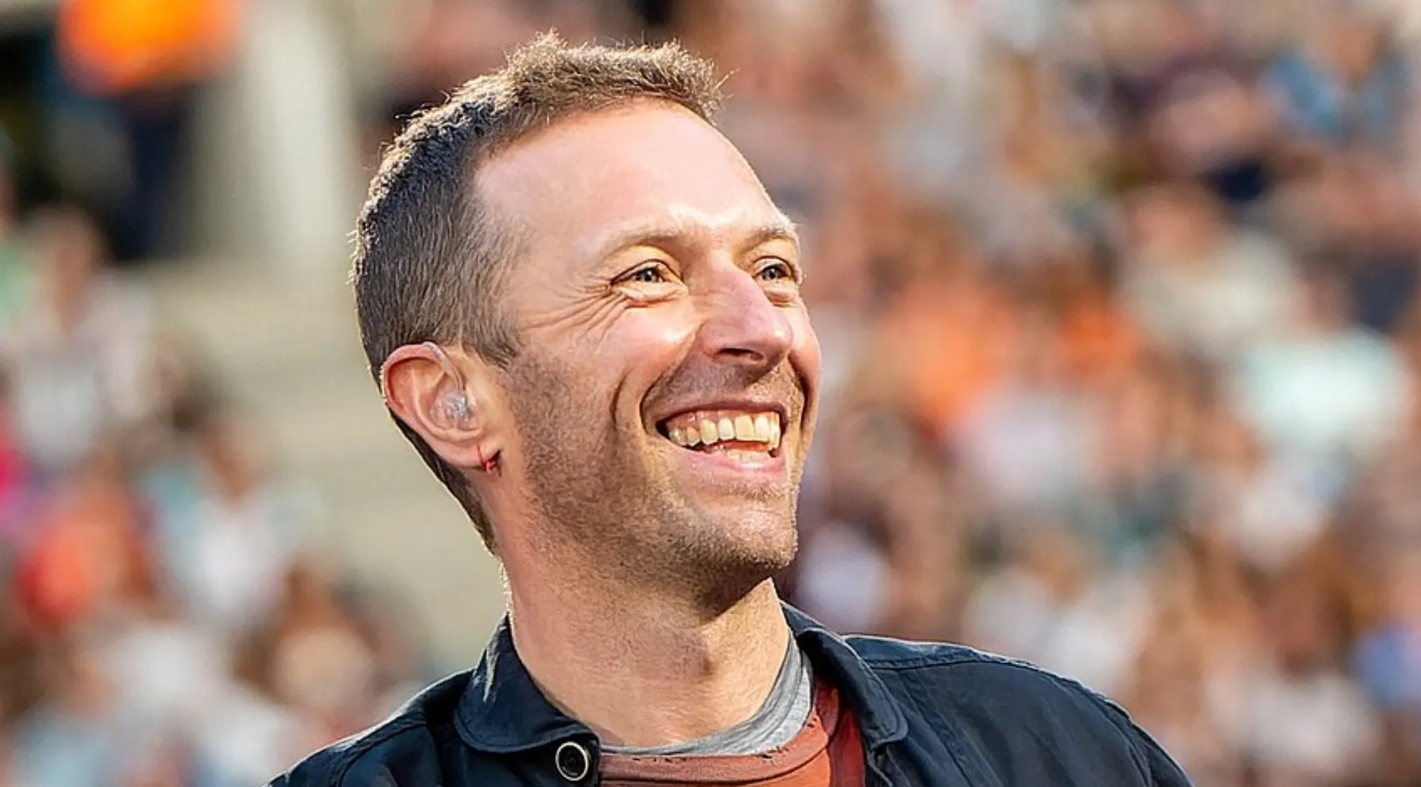 Lead singer performing live on stage, smiling and engaging the crowd in an energetic music challenge moment.