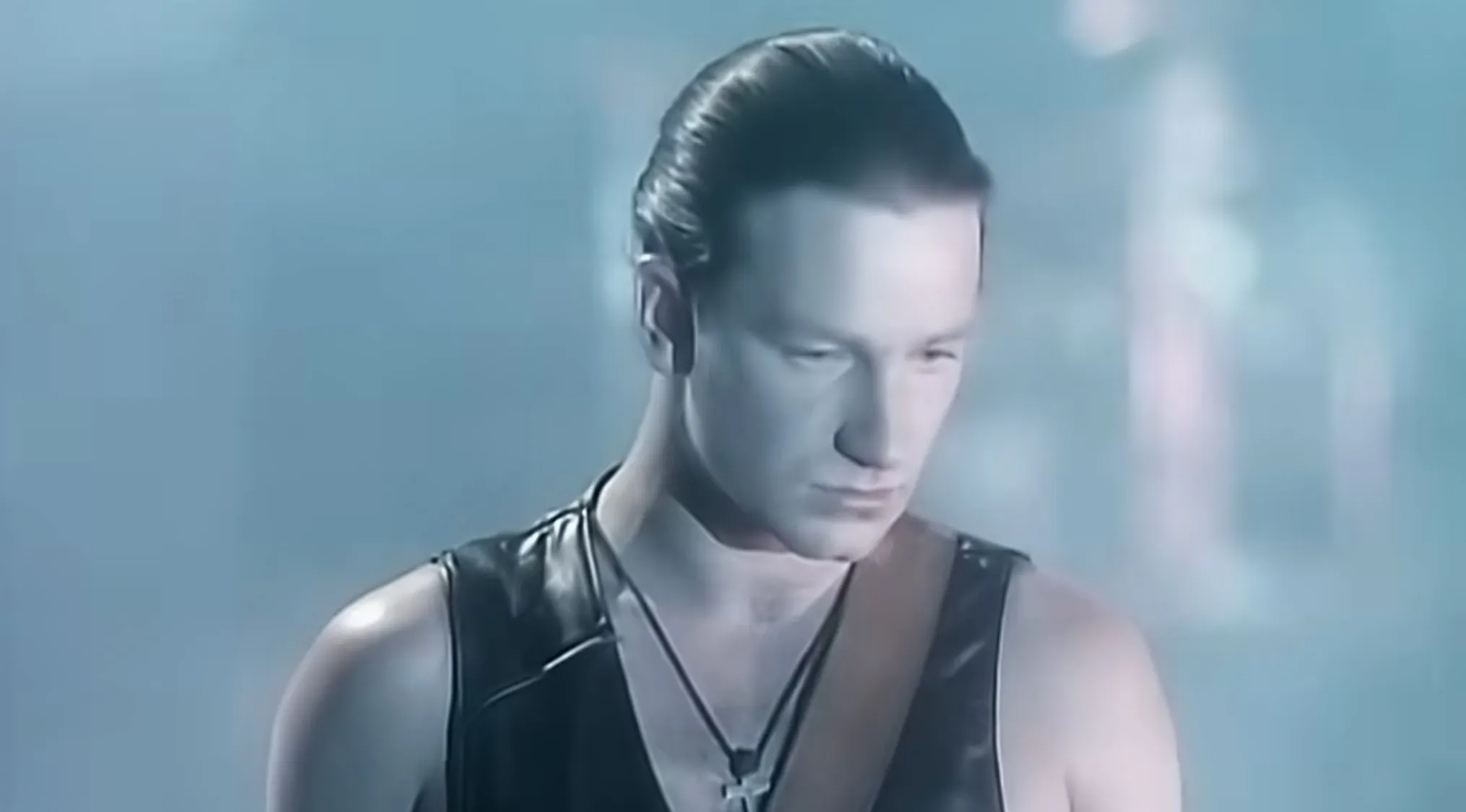 Lead singer performing on stage in a leather vest, representing the music challenge of naming bands from lead singers.