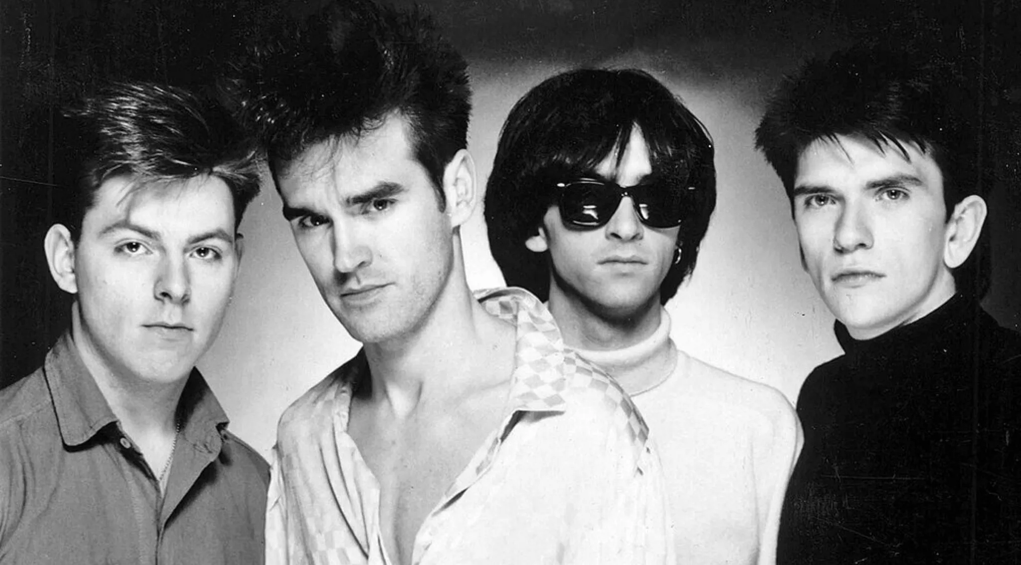 The Smiths band members posing for a black and white photo featuring their lead singer in a music challenge context