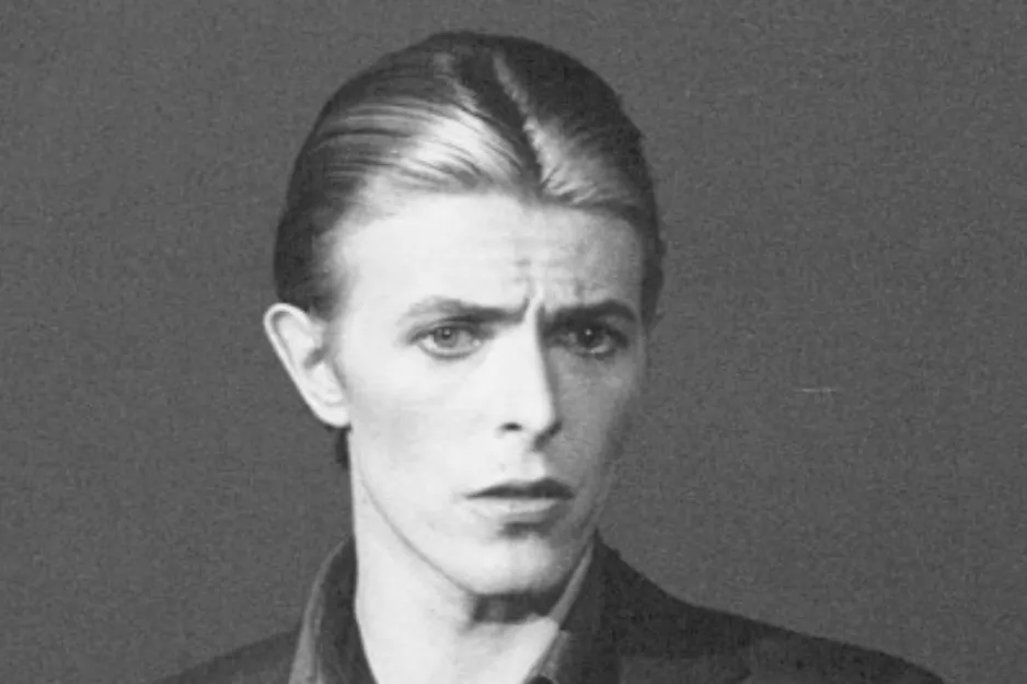 David Bowie in a black and white portrait with slicked-back hair, known as a frontman and primary songwriter.