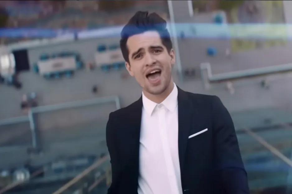 Man in a black suit and white shirt singing outdoors, focusing on frontman, bassist, and primary songwriter of The Police.