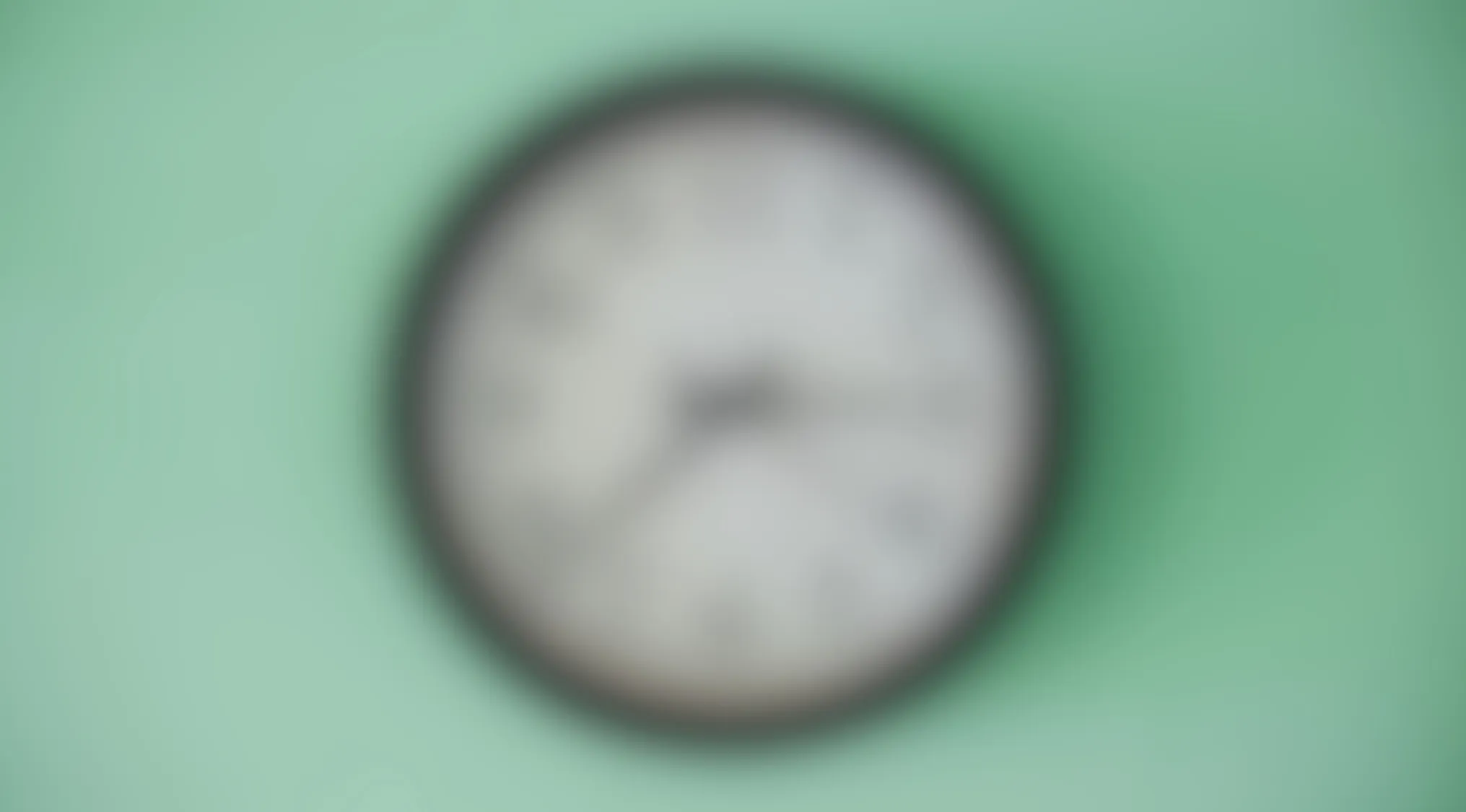 Blurry image of a round object on a green background challenging viewers to make out the object in this picture