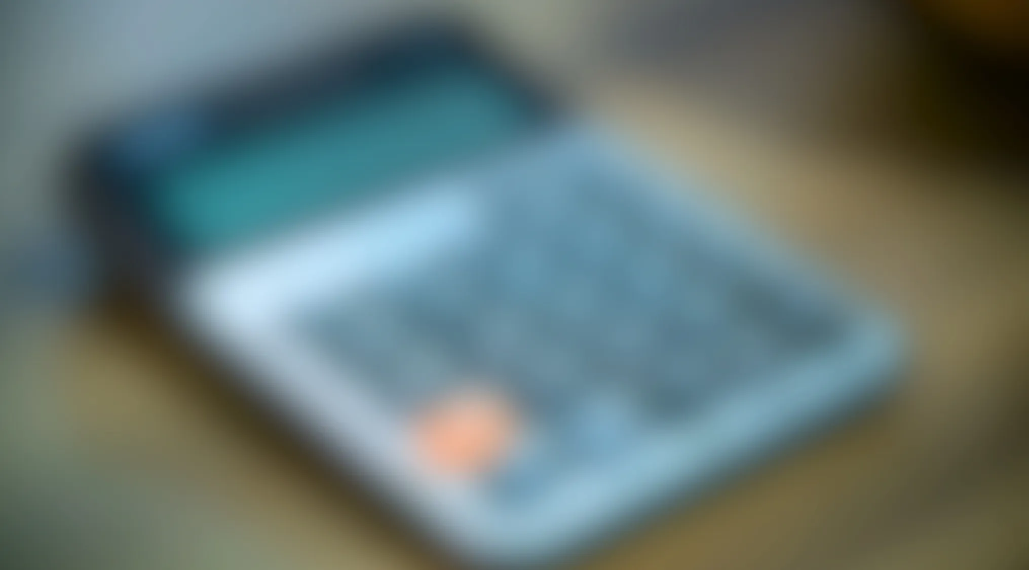 Blurry image showing an electronic device with a screen and buttons on a wooden surface in soft lighting.