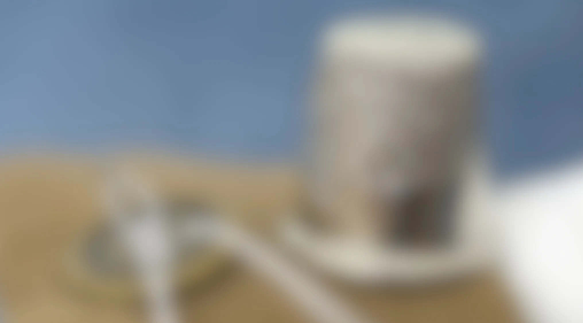 Blurry image of a sewing tool with a measuring tape taking up most of the picture on a wooden surface.
