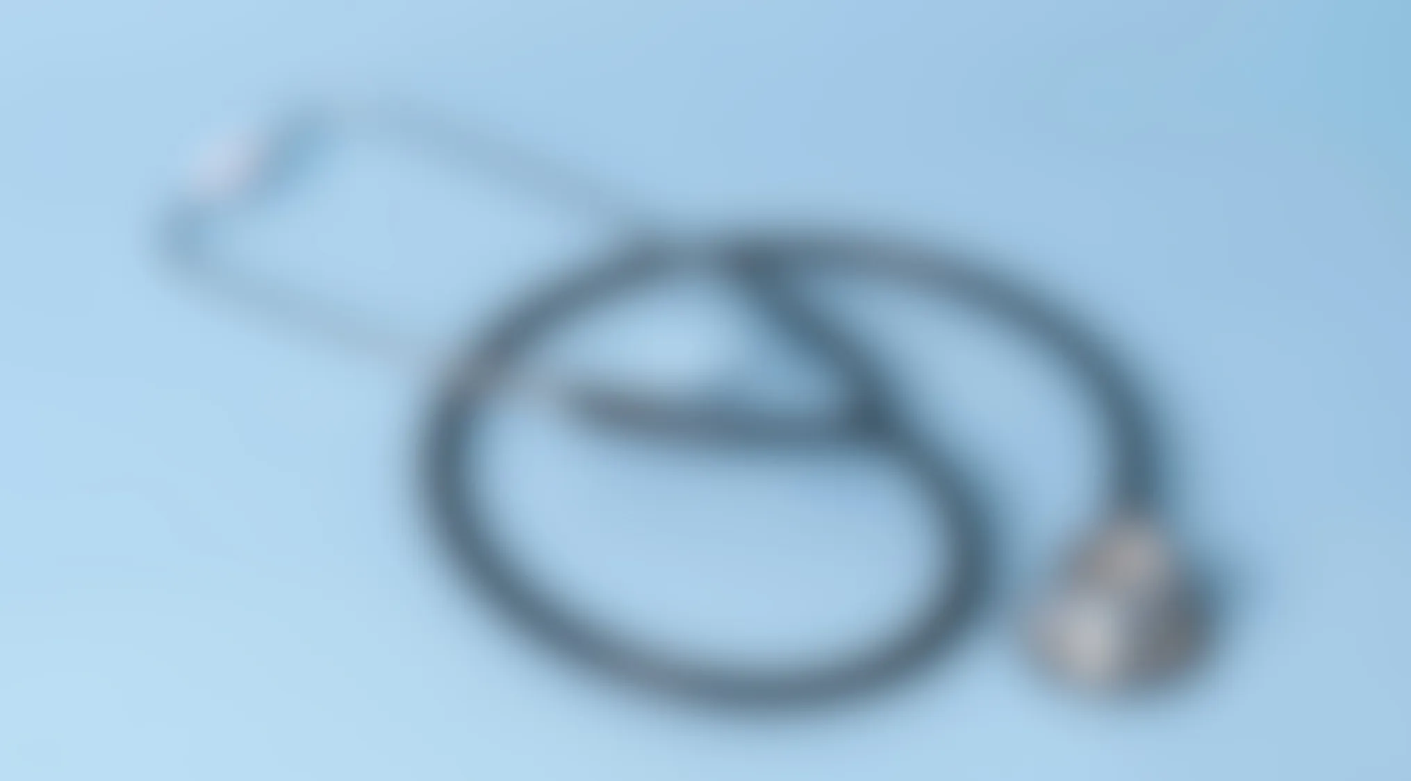 Blurry image showing a coiled object with indistinct details on a light blue background, focusing on identifying the object