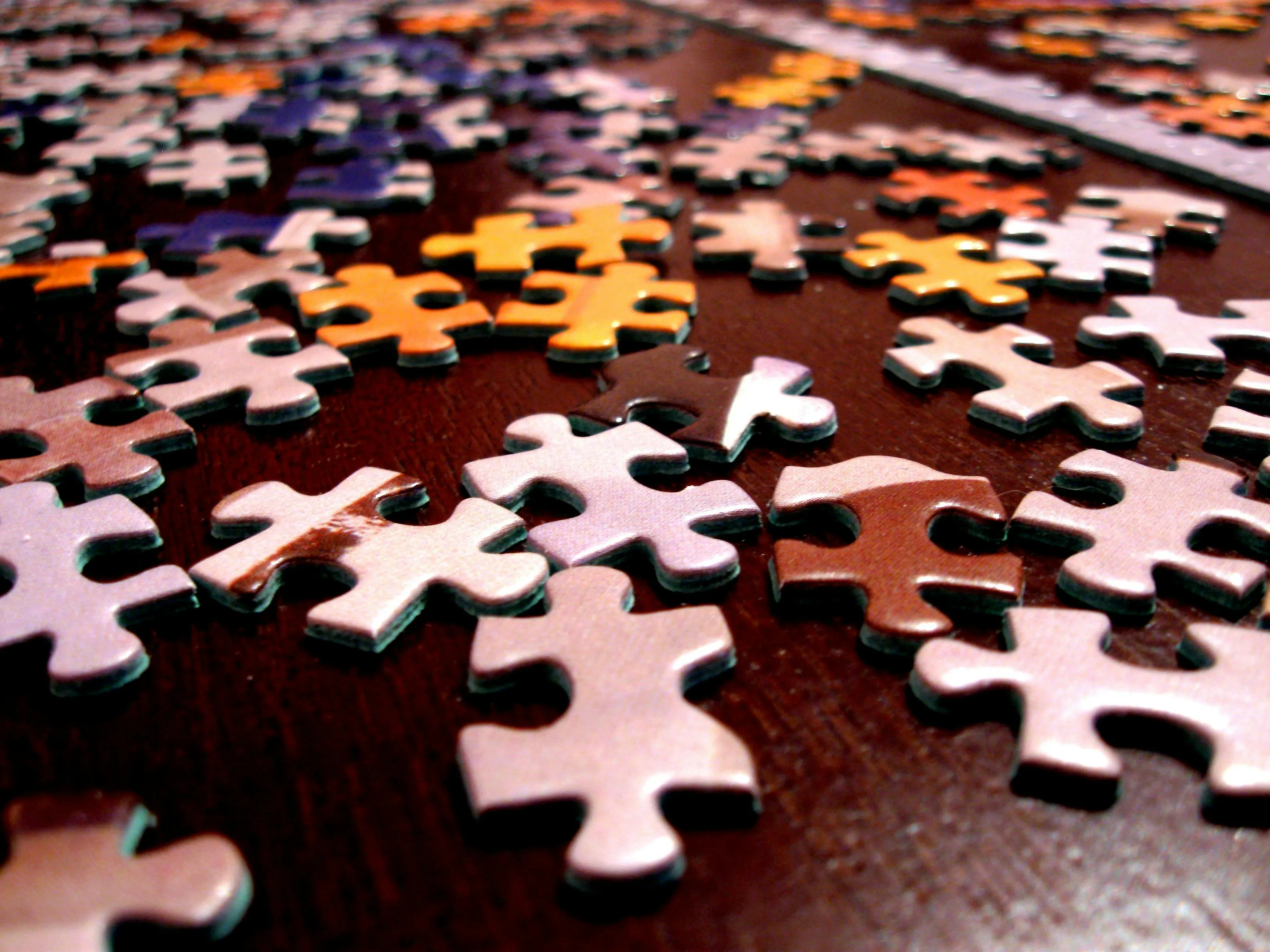 Close-up of colorful jigsaw puzzle pieces scattered on a wooden surface ready for assembly.