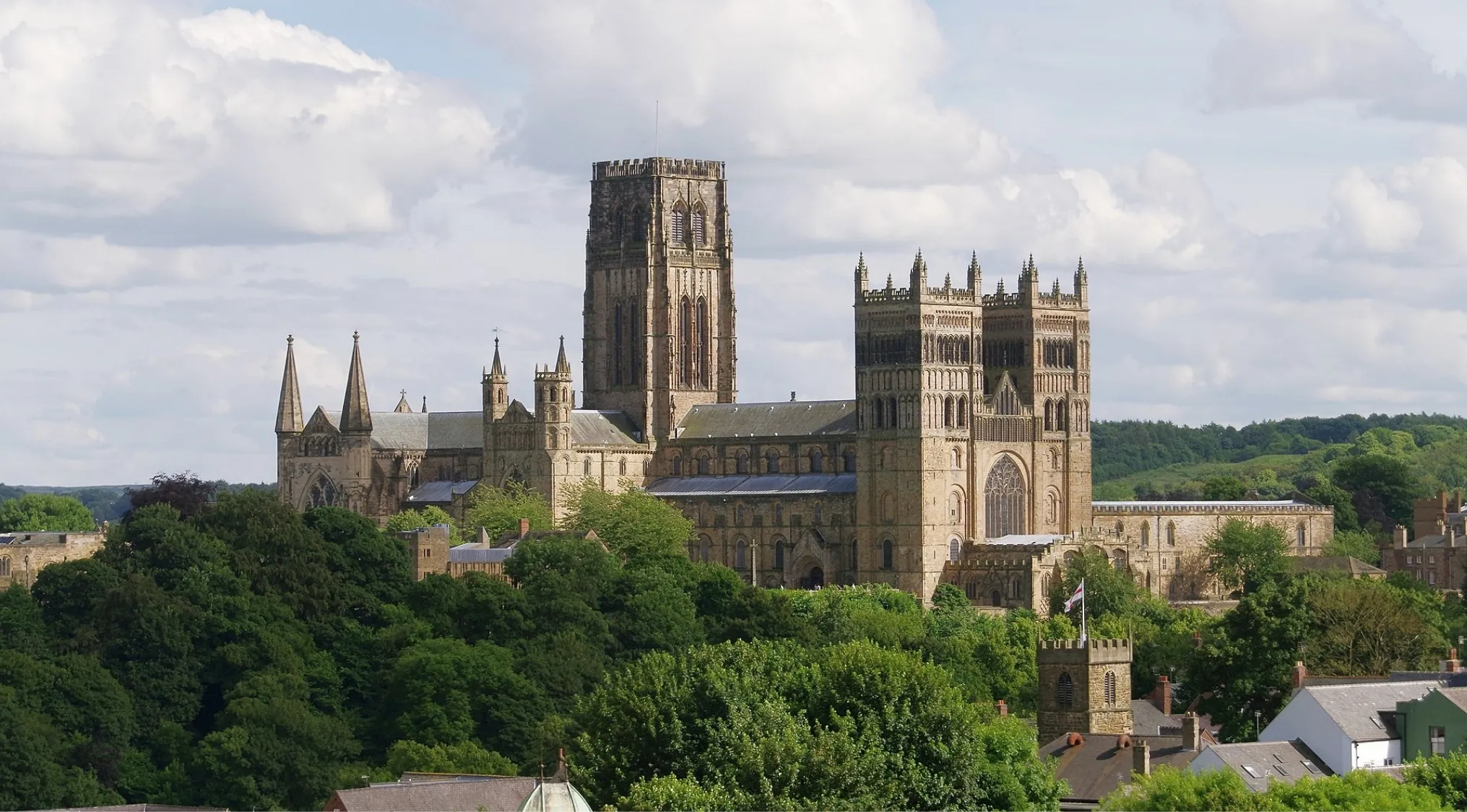 Durham Cathedral showcasing Norman architecture with Romanesque style features and lush greenery surrounding it.