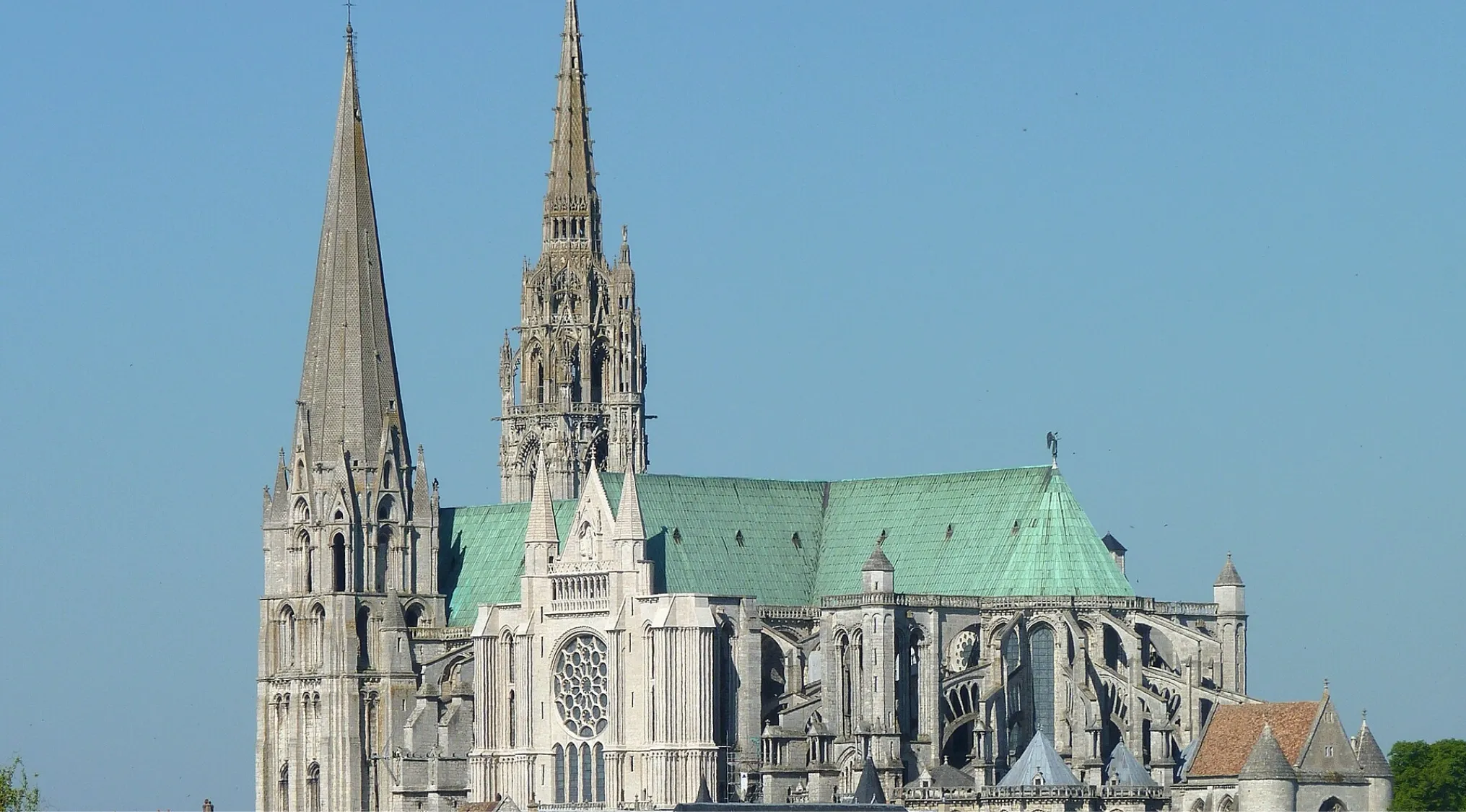 Gothic architectural style of Chartres Cathedral with detailed stone spires and large rose window under a clear sky.