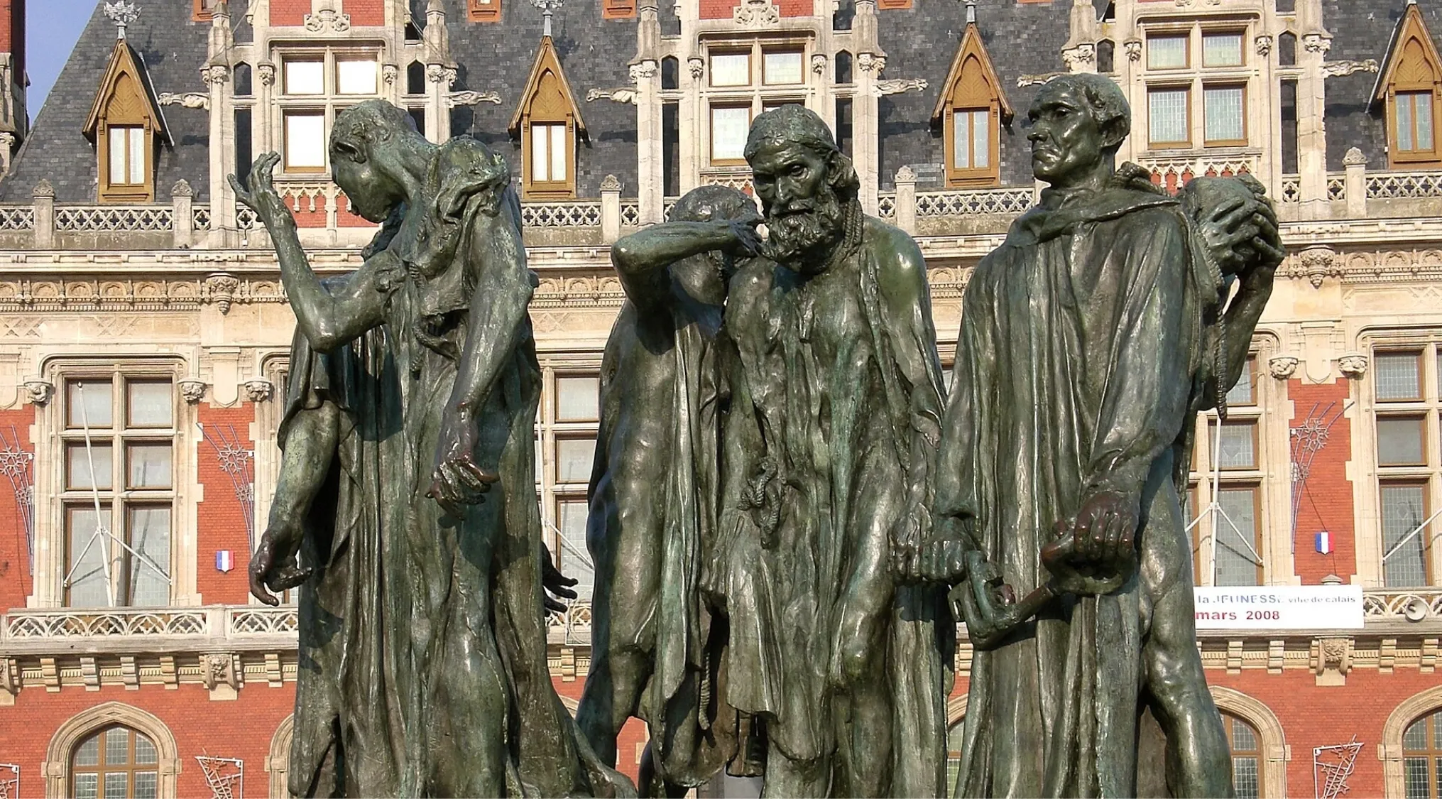 Bronze sculpture of six emotional figures, The Burghers of Calais, showcasing realism in detailed human expressions.