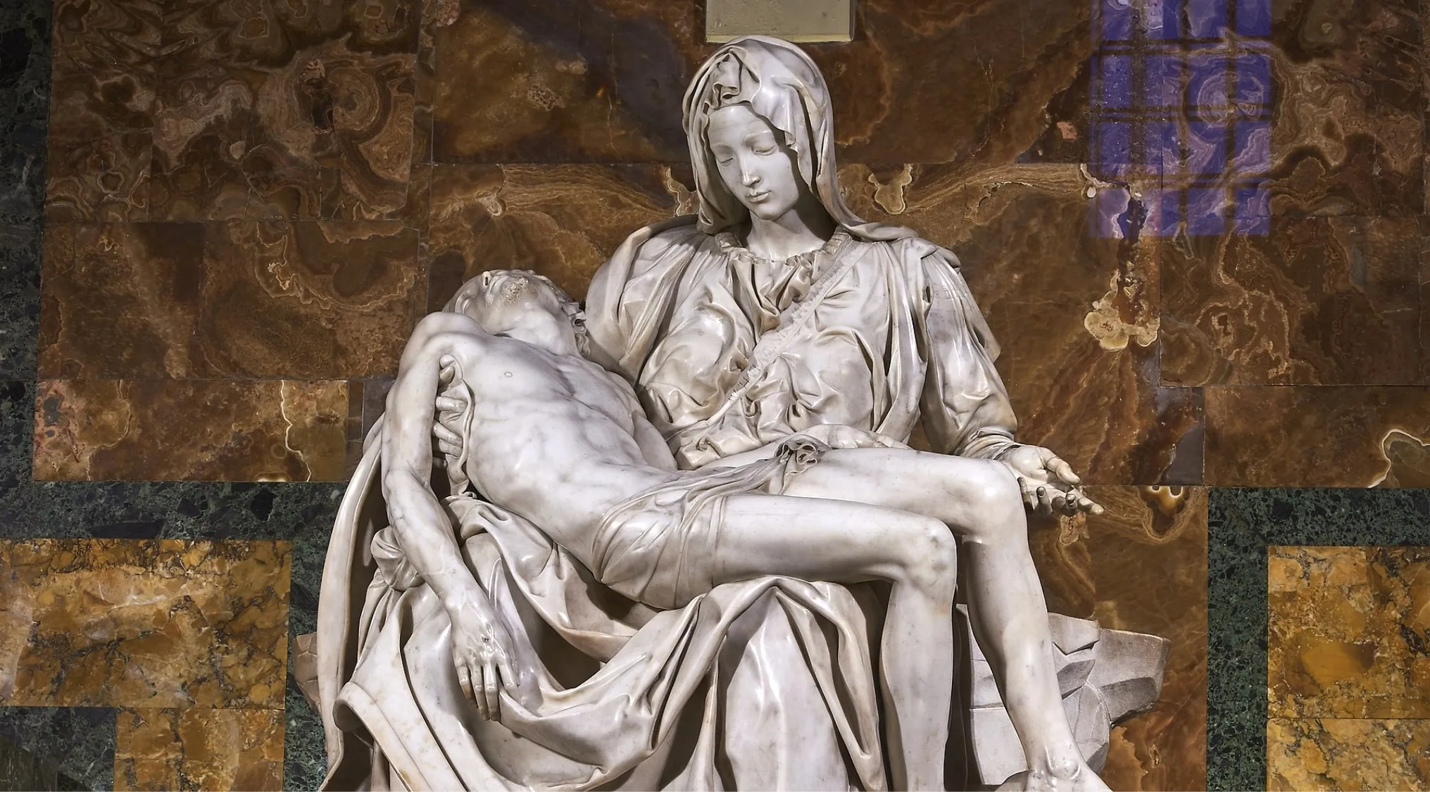 Pietà sculpture showing realistic depiction of Mary holding Jesus after the crucifixion with detailed drapery and anatomy.