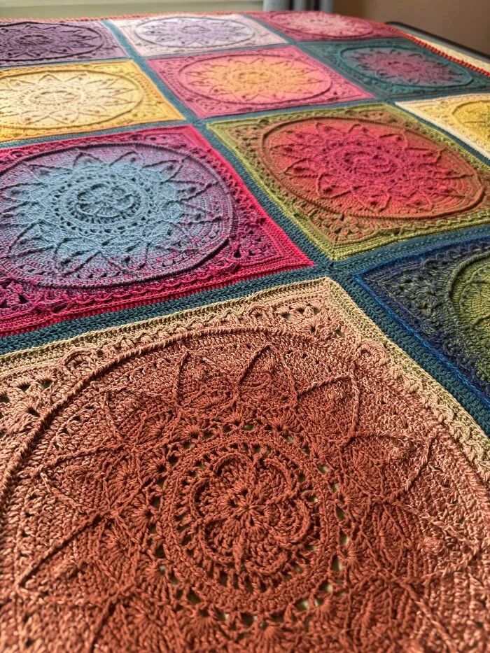 Multicolored crocheted blanket featuring intricate mandala-inspired square patterns