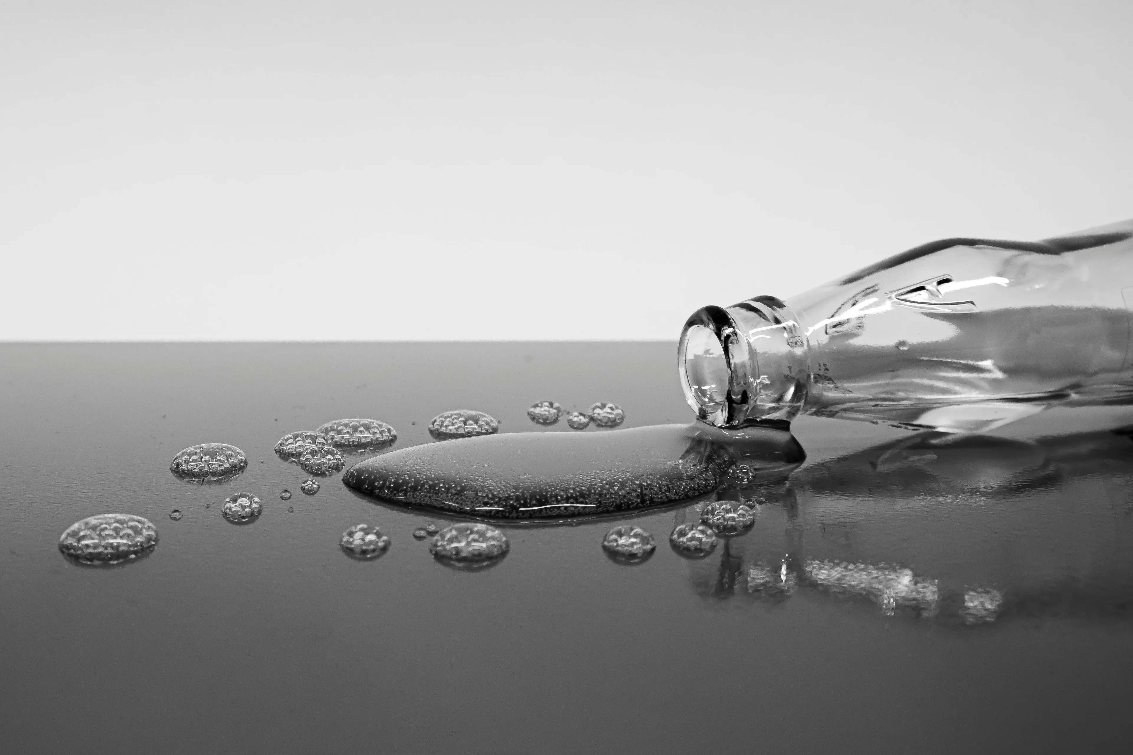 Glass bottle tipped over with liquid metal spilling, illustrating the only metal liquid at room temperature for high IQ quiz.