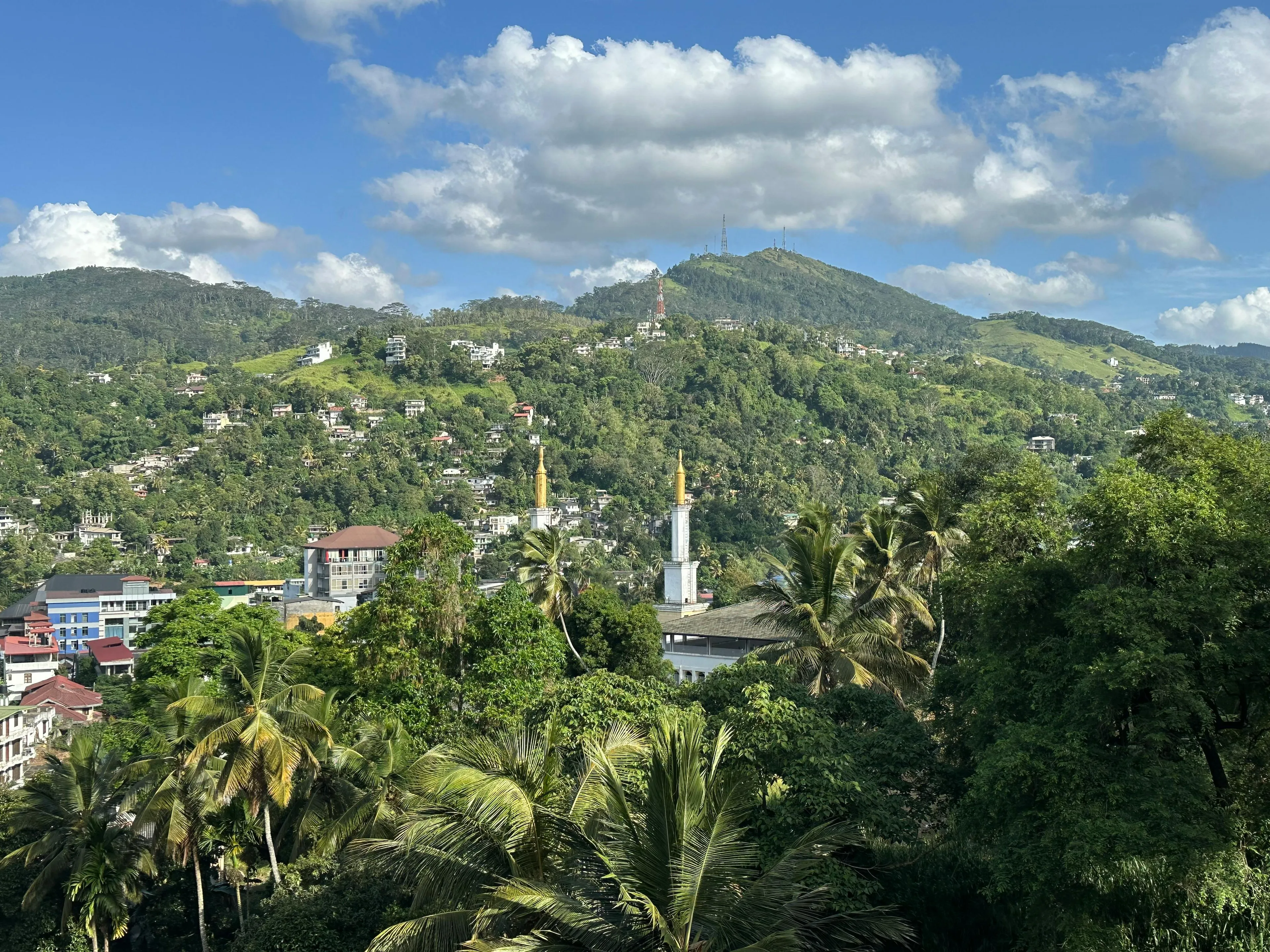 Lush green hills and buildings under a blue sky in Sri Lanka, the modern-day country once named Ceylon