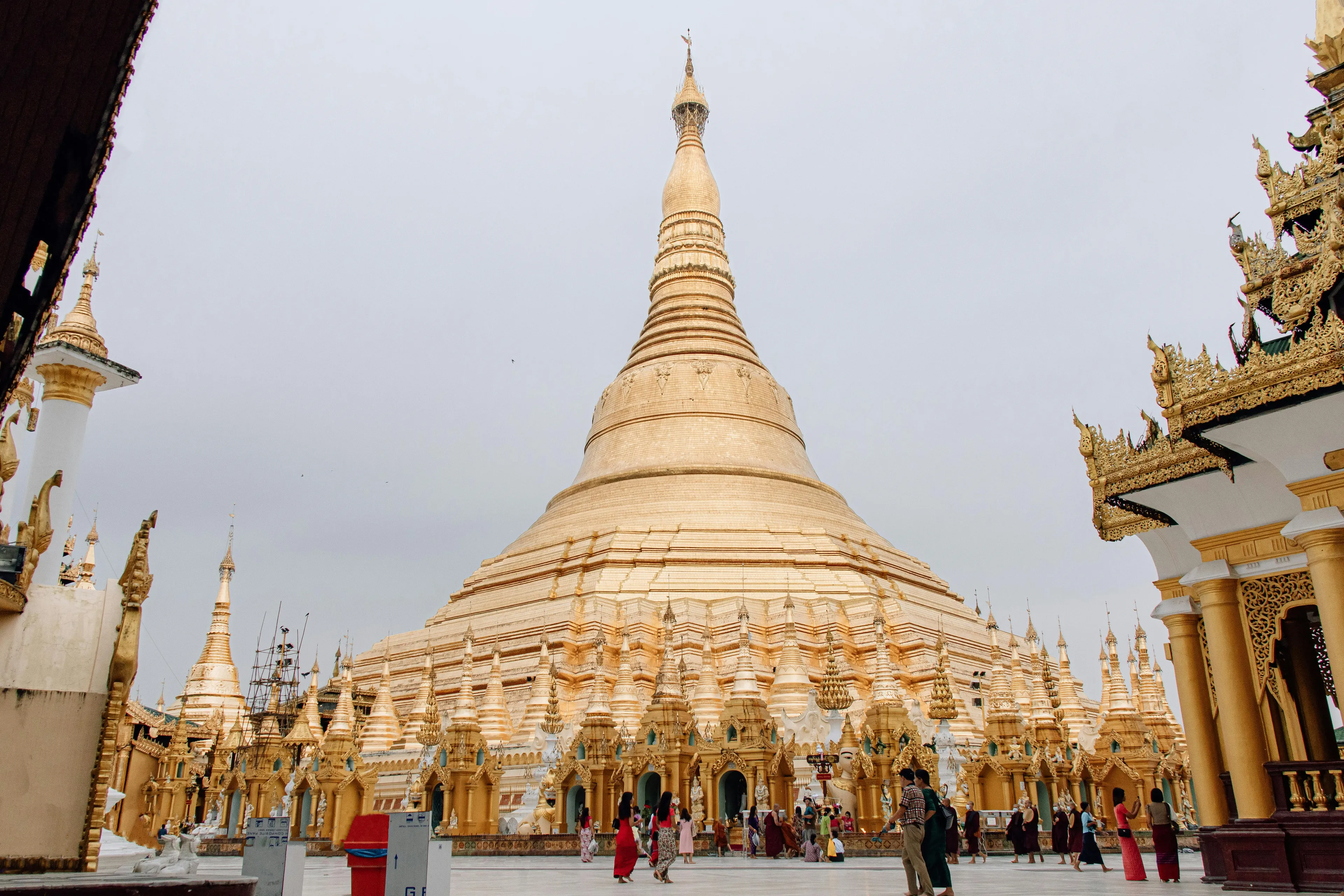 Golden Shwedagon Pagoda in Myanmar with visitors, showcasing traditional Burmese architecture and cultural heritage.
