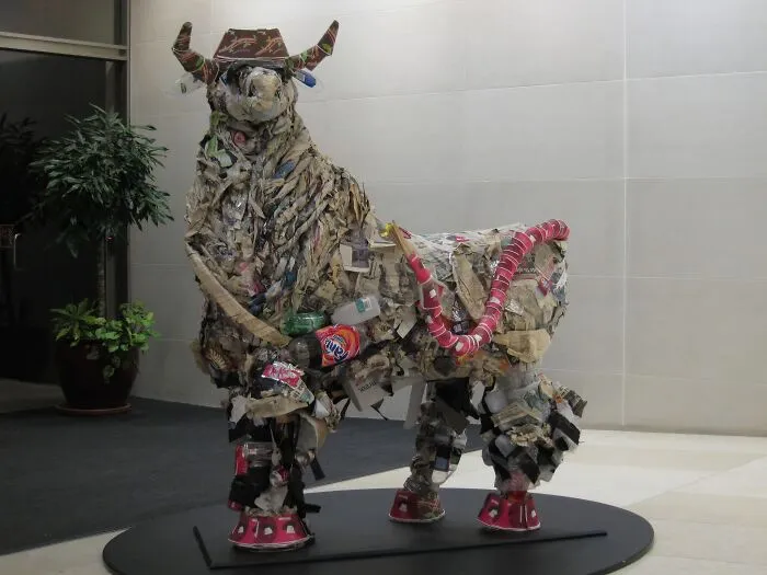 A large bull sculpture, creatively assembled from trash and recycled materials, showcasing useful artistic expression.