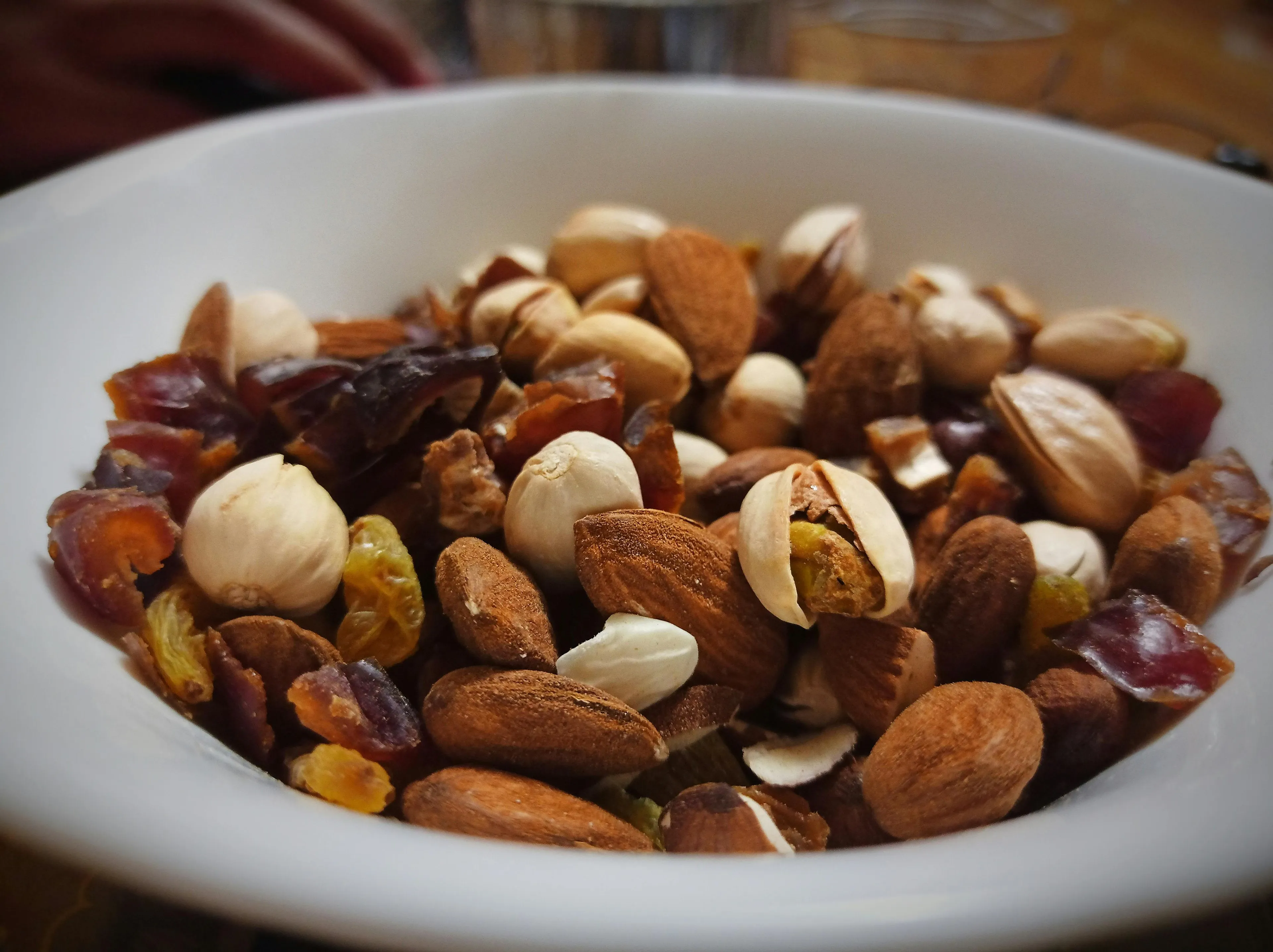 Bowl of trail mix with almonds, pistachios, hazelnuts, raisins, and dried fruit pieces for an emergency snack.