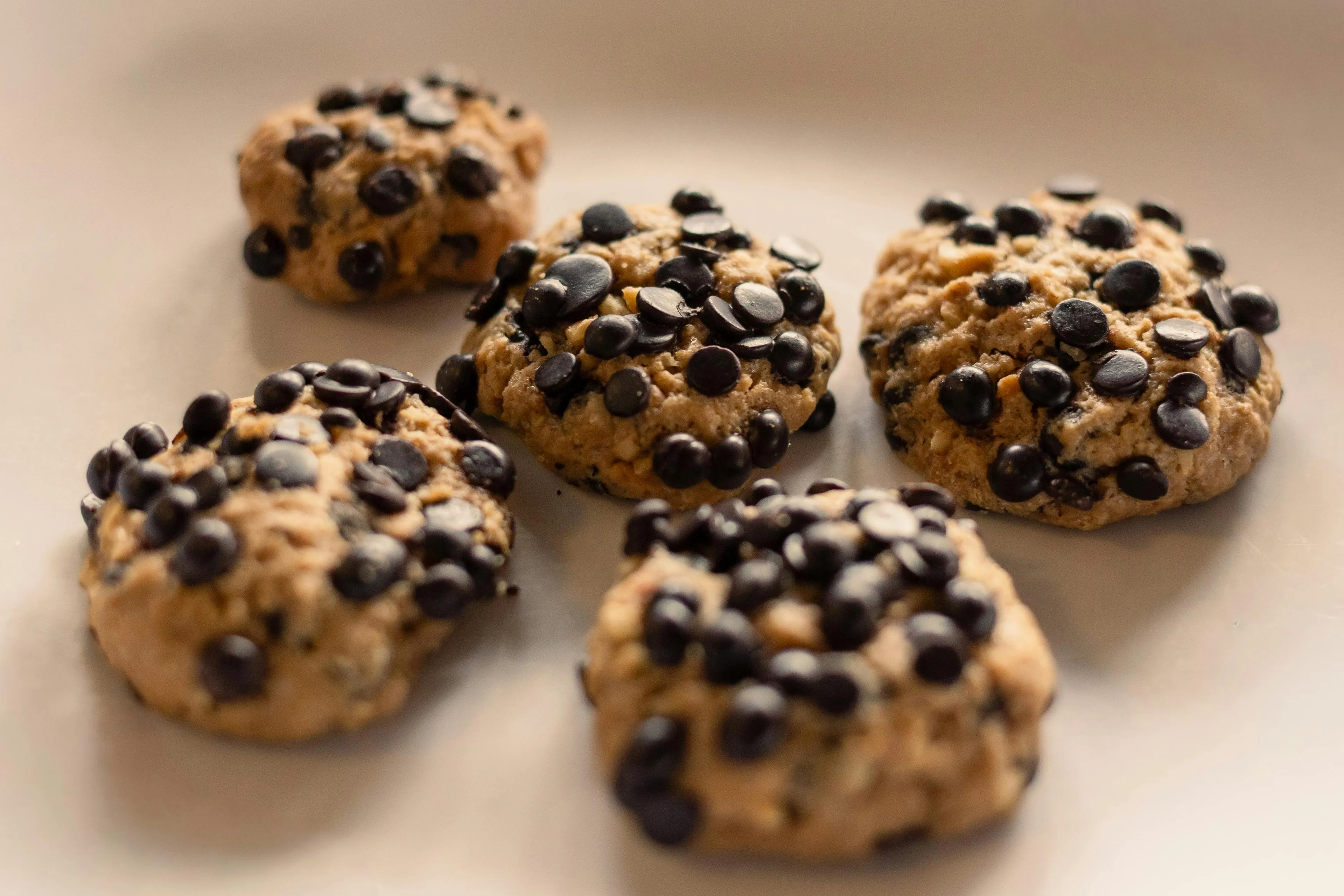 Homemade cookies with chocolate chips arranged on parchment paper, a perfect snack to stash in your bag.