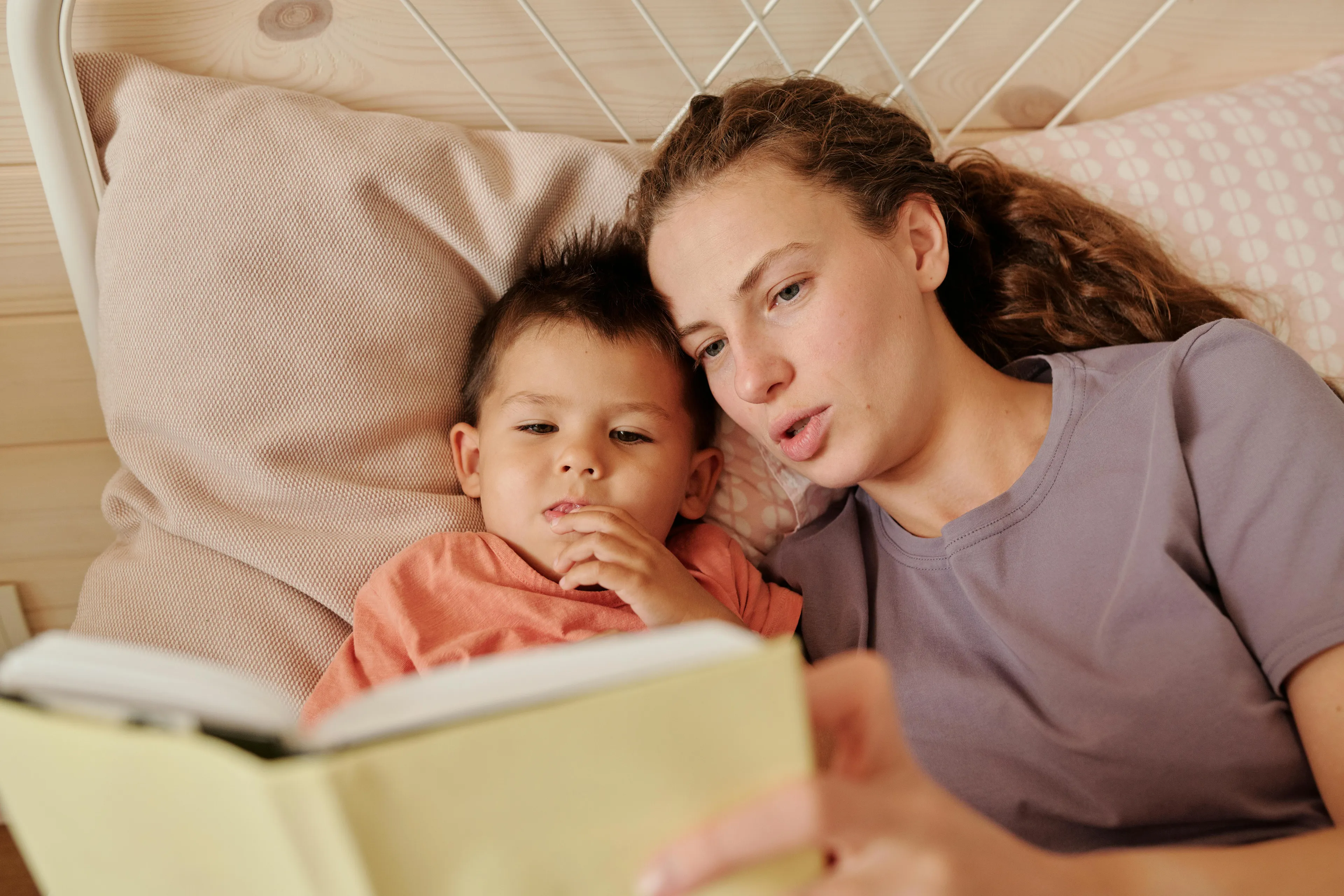 Mother and son lying on bed sharing bedtime stories during their favorite time of day together.