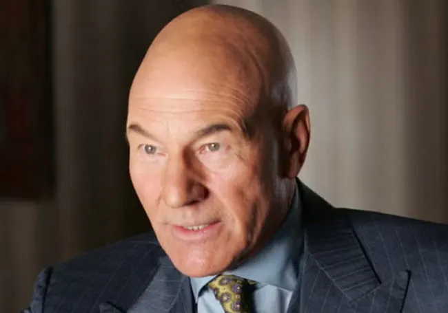 Bald man in a suit and patterned tie representing a Professor X superhero mentor style in a professional setting.
