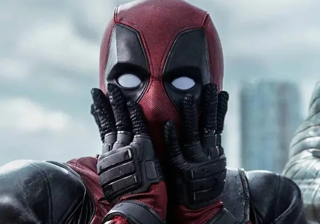 Deadpool in red and black suit with gloved hands on face, showcasing unique superhero mentor style expression.