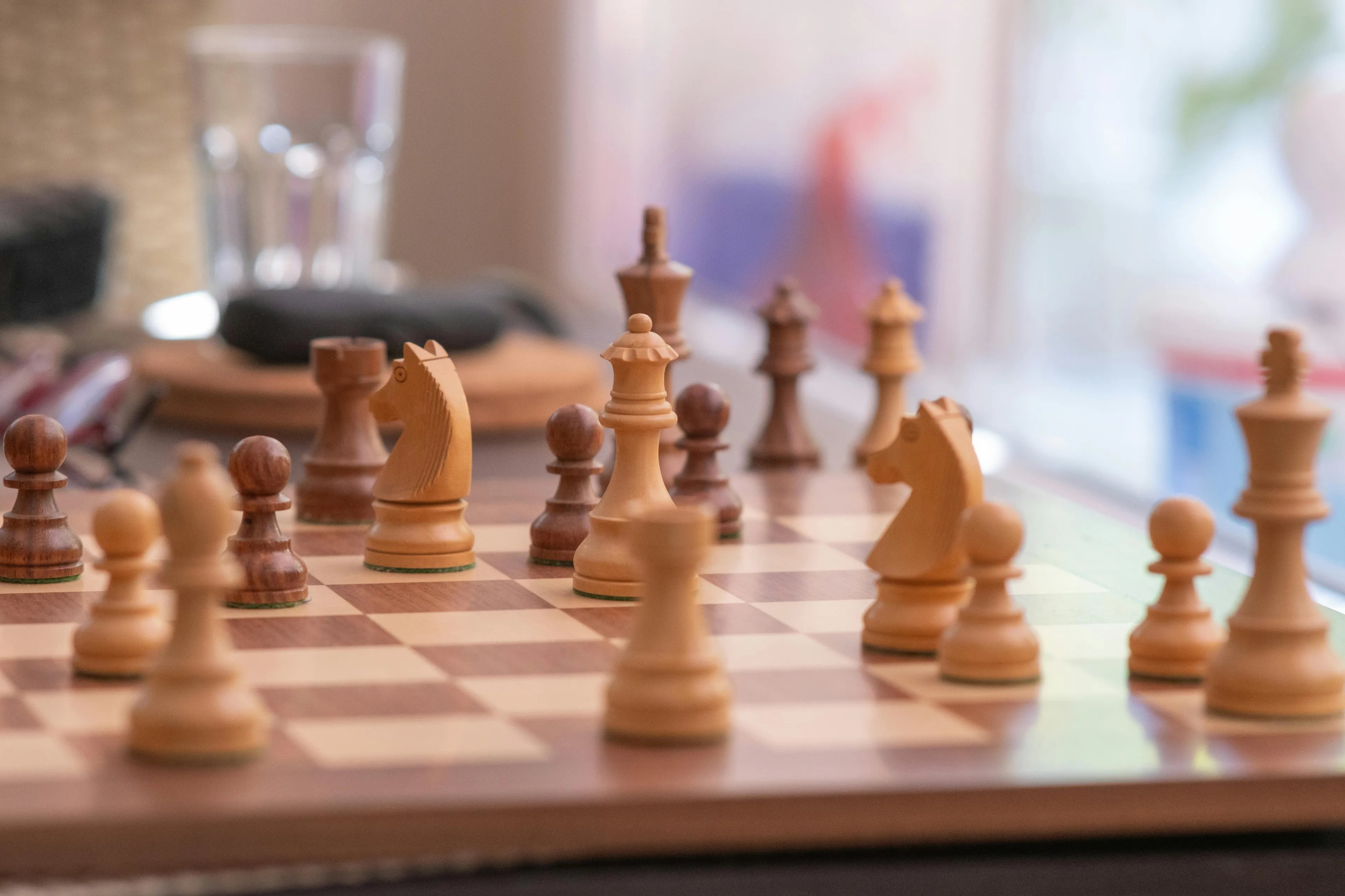 Chess pieces arranged on a wooden chessboard during a game, highlighting the classic board game strategy.