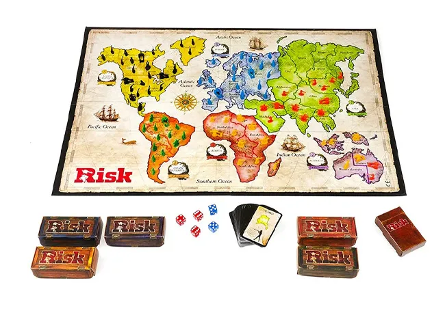 Risk board game setup with colorful world map, dice, and playing cards arranged on a white background.