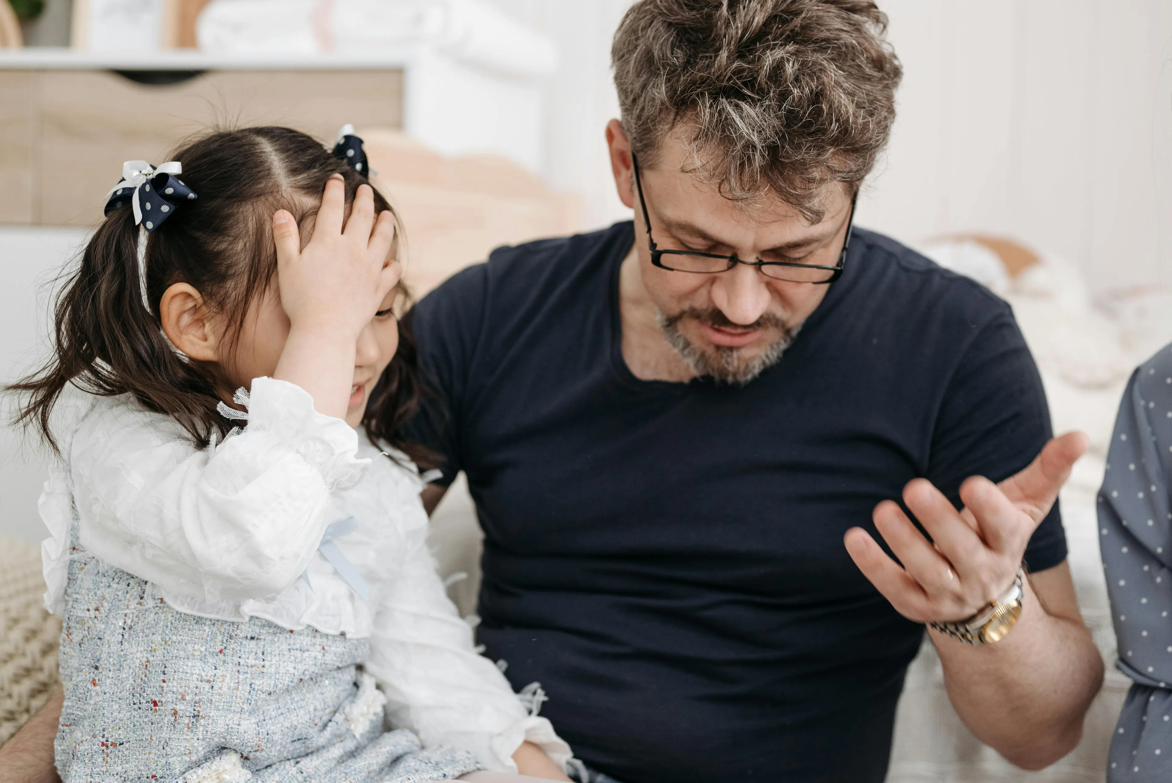 Father and daughter discussing parenting style while working on a last-minute school project at home.