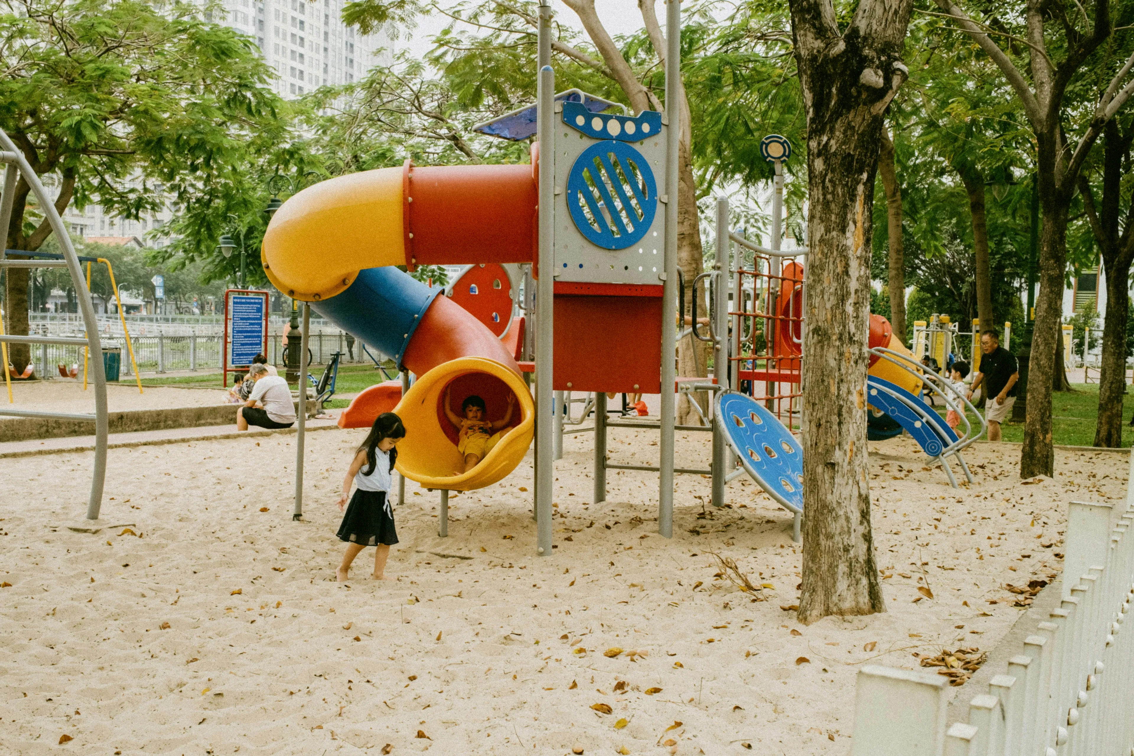 Children playing on a colorful playground slide, illustrating different parenting styles in social interactions.