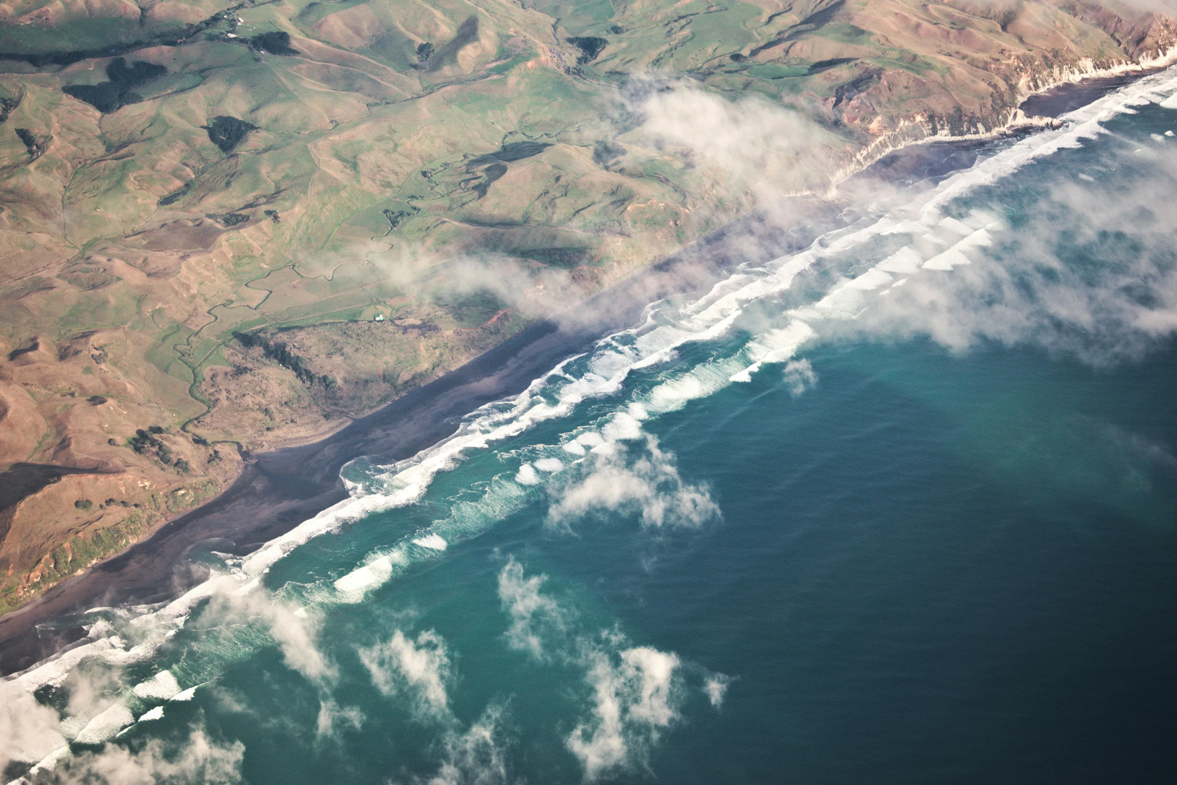 Aerial view of coastline with waves and fog, illustrating geography related to countries bordering Atlantic Ocean and Mediterranean Sea.