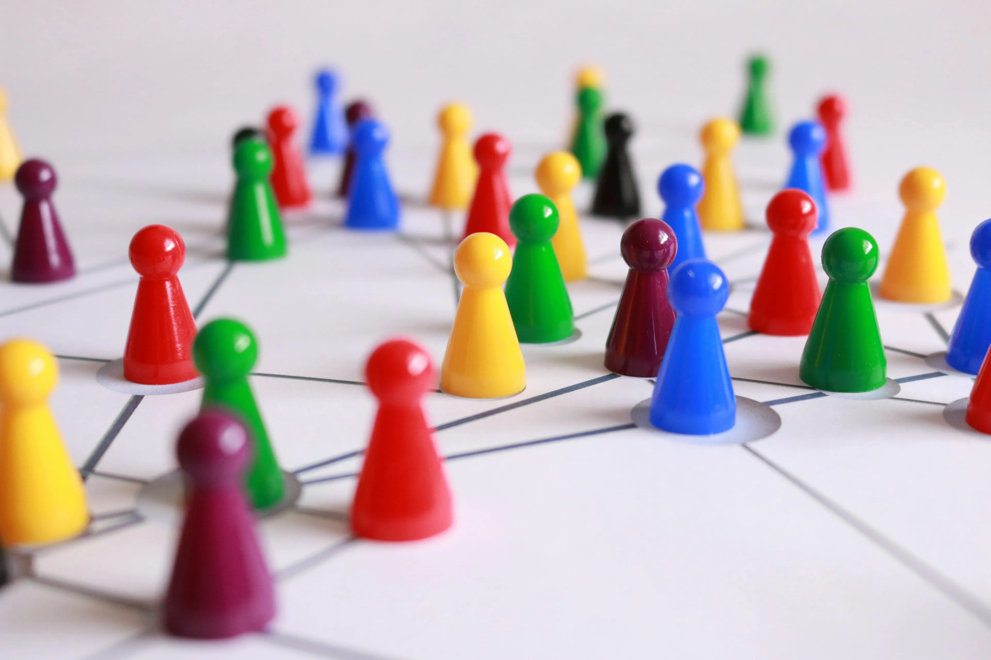 Colorful game pieces connected by lines on a white surface, representing geography edition connections between cities.