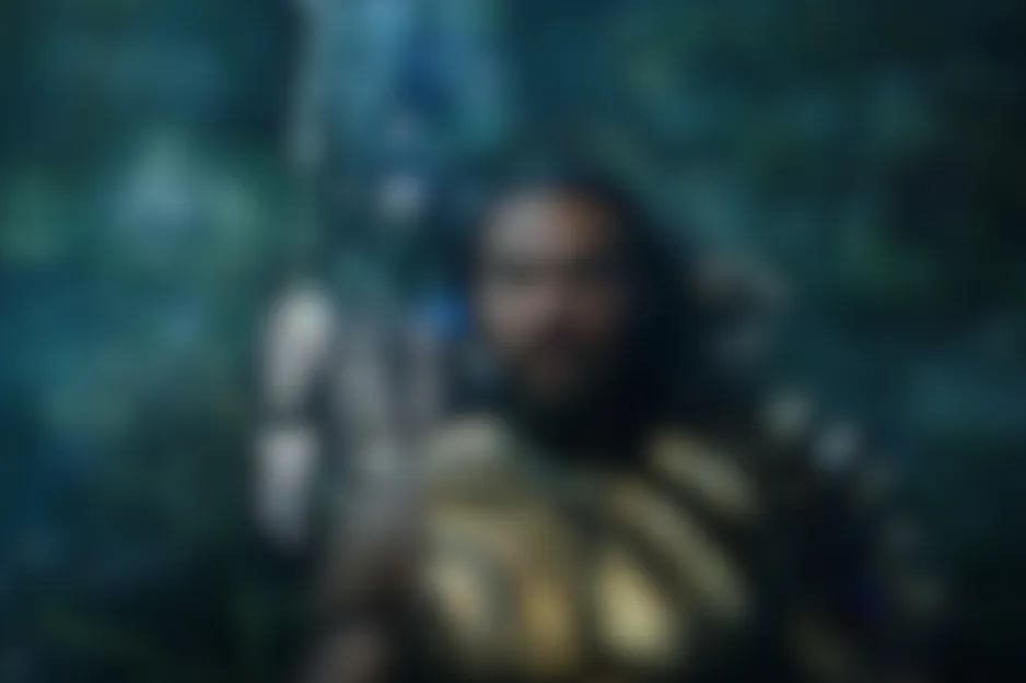 Blurred scene from Aquaman showing a dark-haired, bearded character in dim, blue-green lighting.