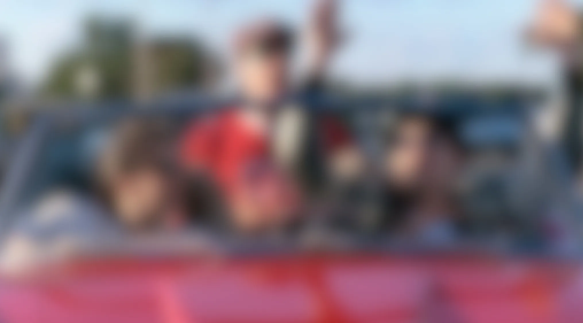 Blurry Movie Scenes of people in a red car, one in a red jacket making a peace sign. Can you make out the movie?
