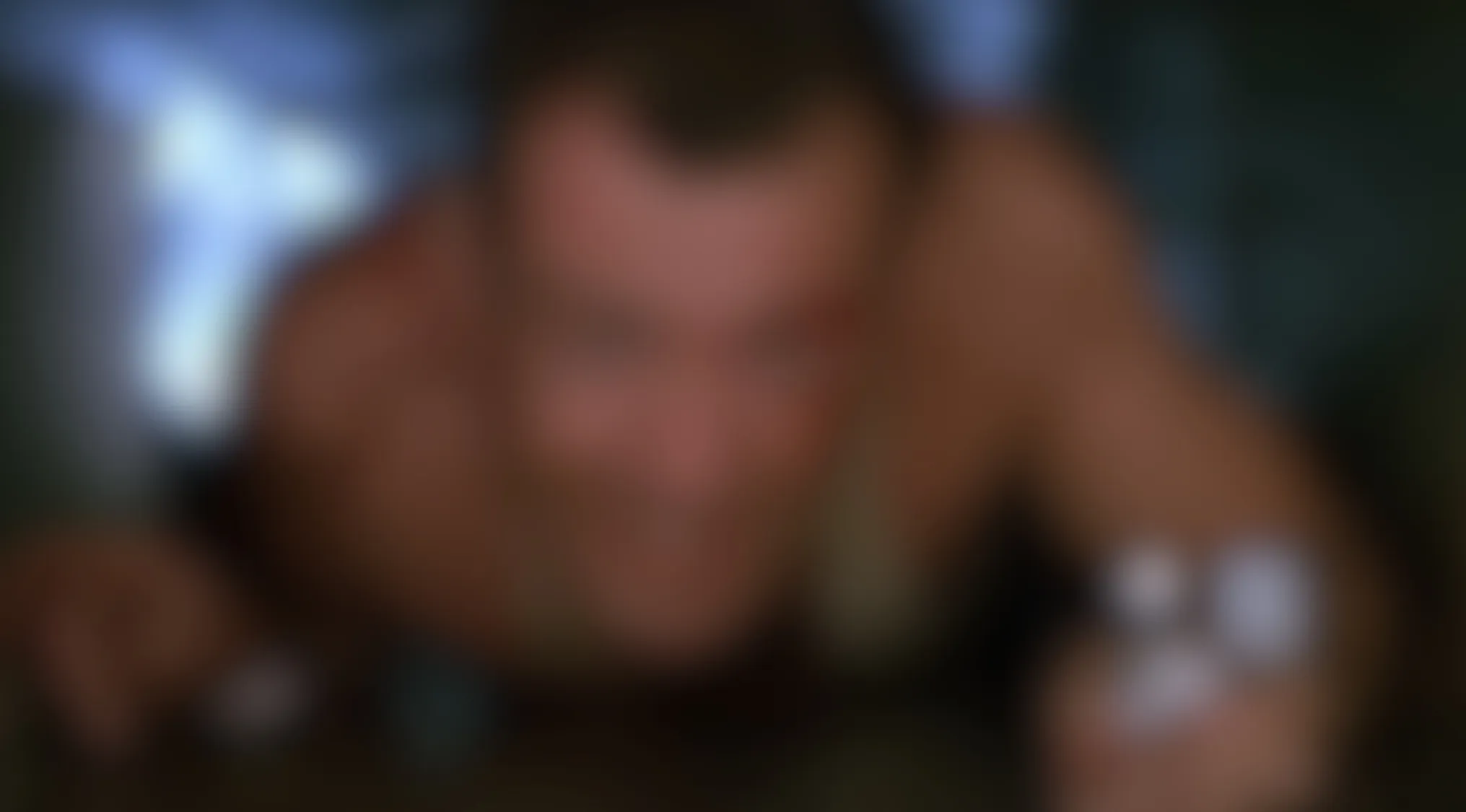 A blurry movie scene of a man's out-of-focus face and torso, looking forward from a dark, confined space.