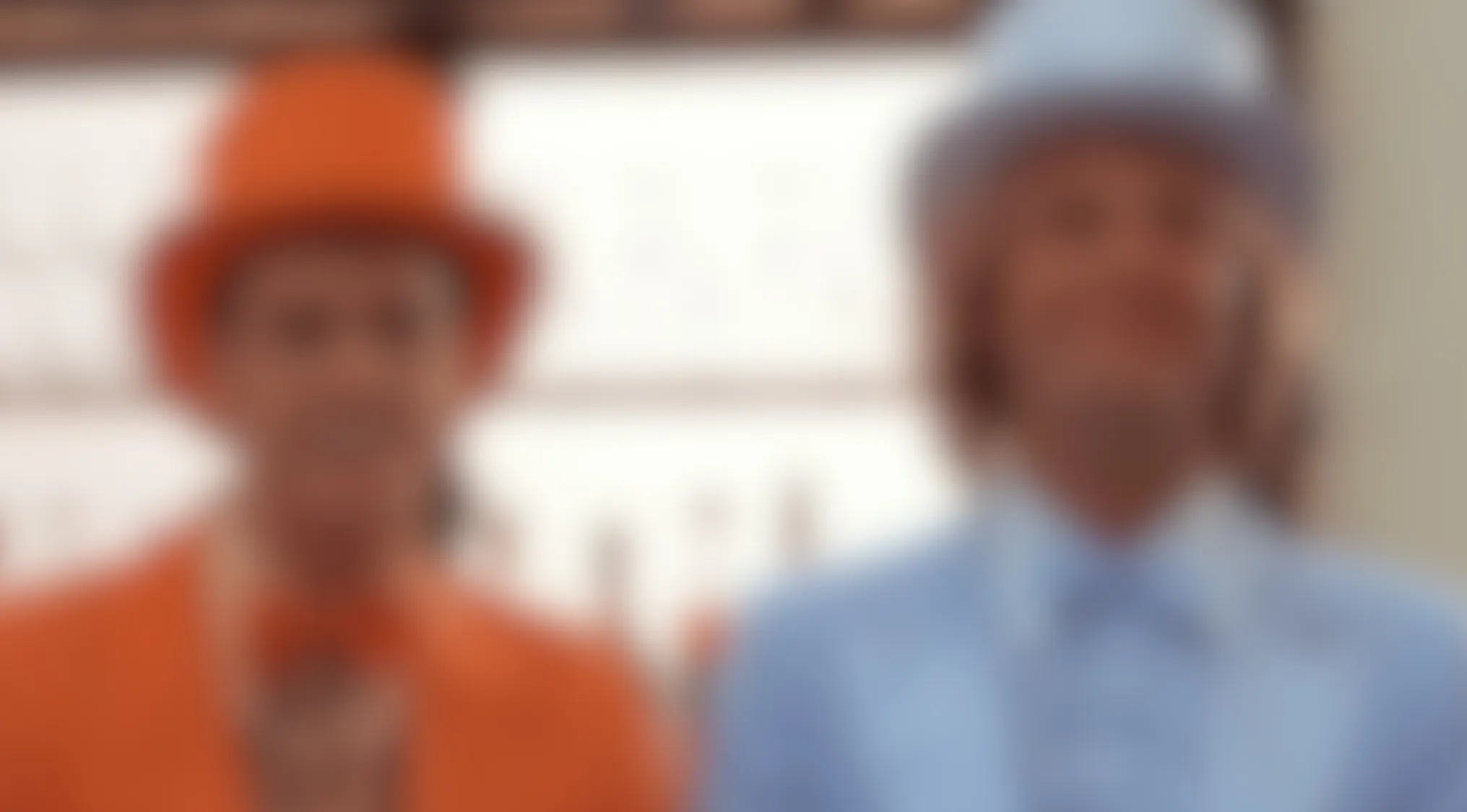 This blurry movie scene features two men in iconic orange and blue suits with matching hats. Can you identify the film?