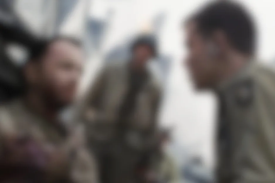 Blurry scene from Saving Private Ryan (1998) shows three soldiers in tan uniforms, two appearing to converse.