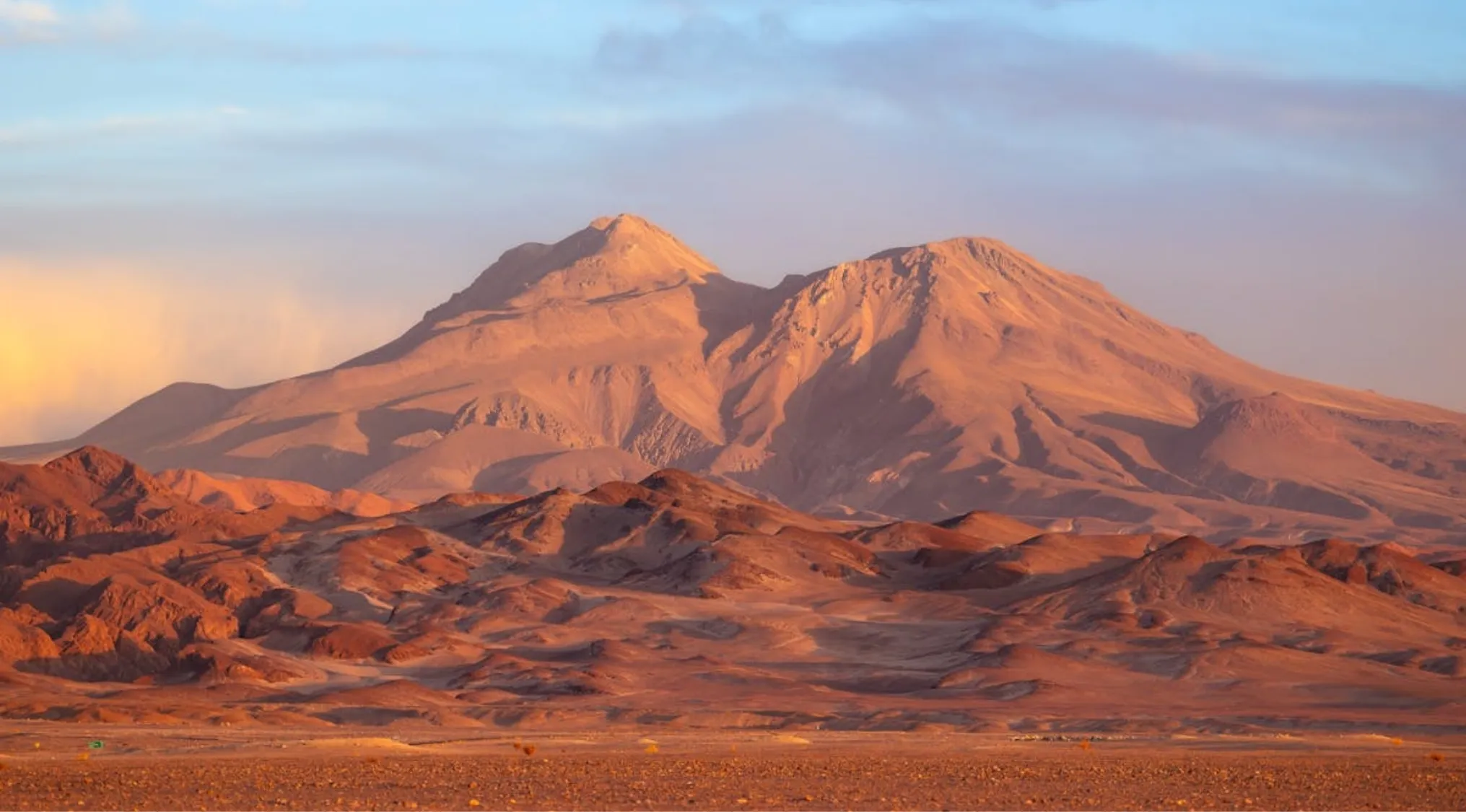 Vast arid desert mountains and hills under a dramatic sky, a world where it never rains, reminiscent of Thomas Edison's test.